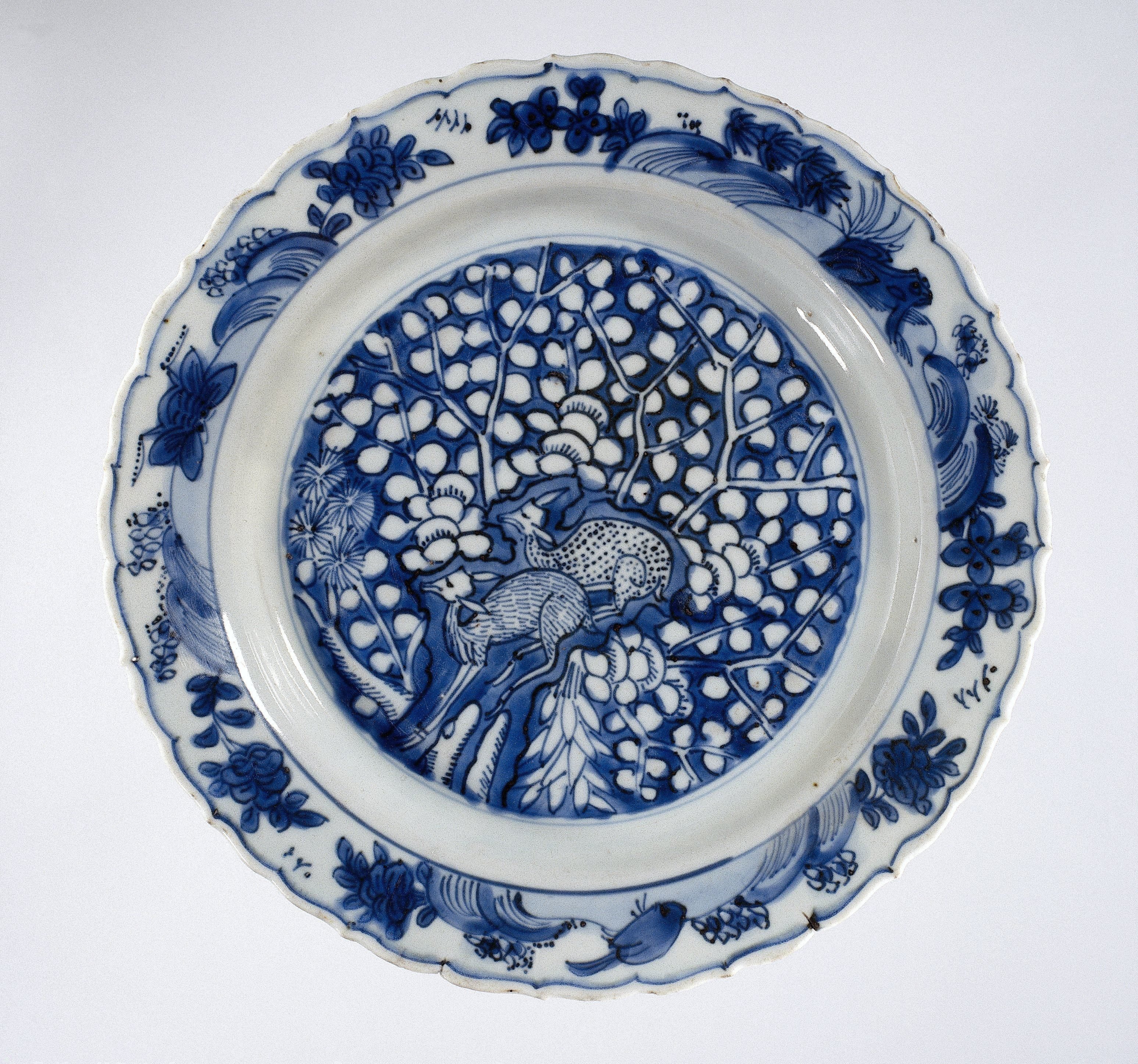 Plate with two deer near a rock and flowering trees