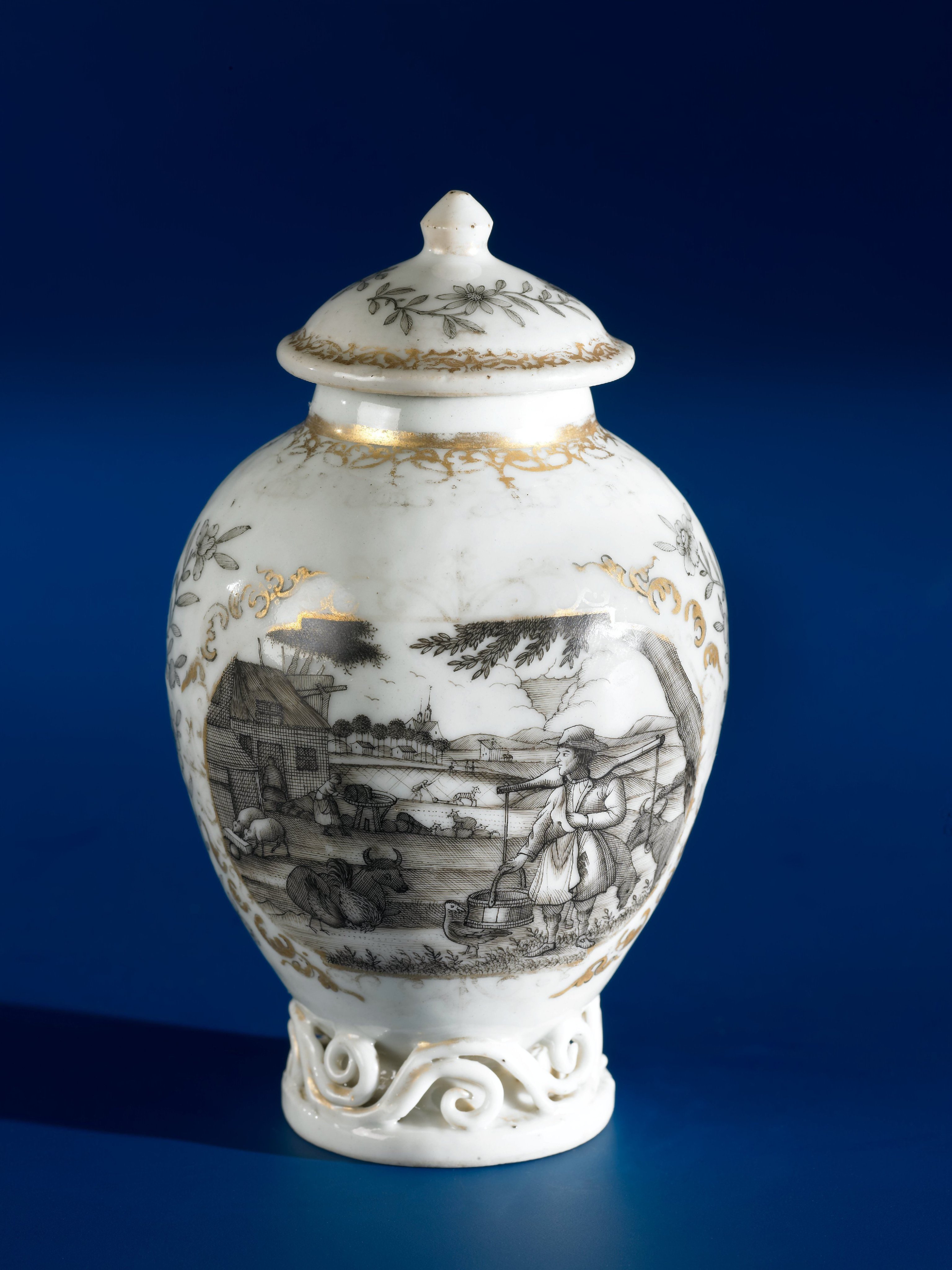 Ovoid tea caddy with a European country scene in two panels with flower sprays in between