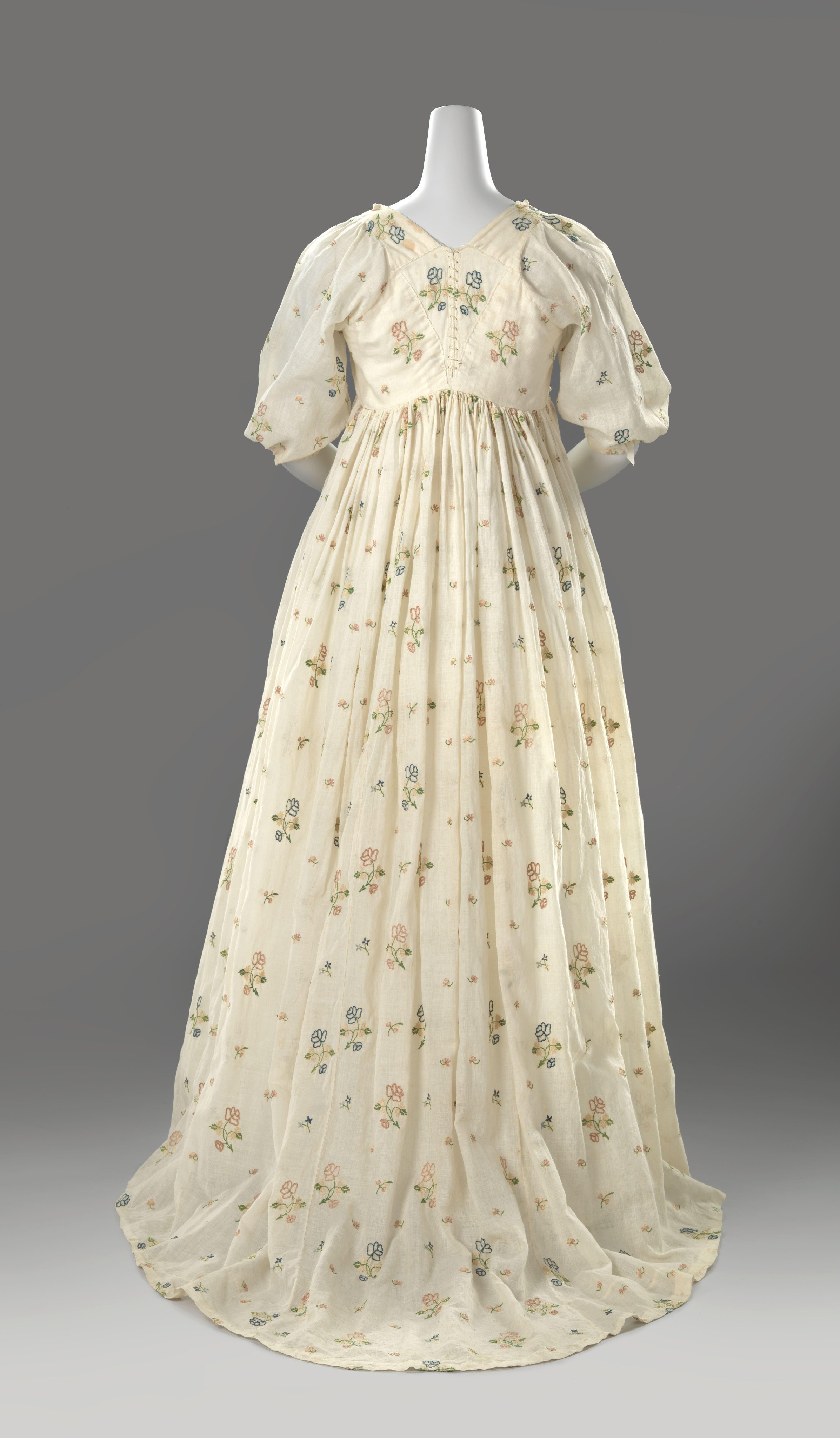 Japon van los geweven katoen, lang met hoge taille, ronde hals, korte mouwen, gerimpelde rok met aangeknipte sleep, versierd met strooimotief van bloemen getamboereerd met veelkleurige zijde