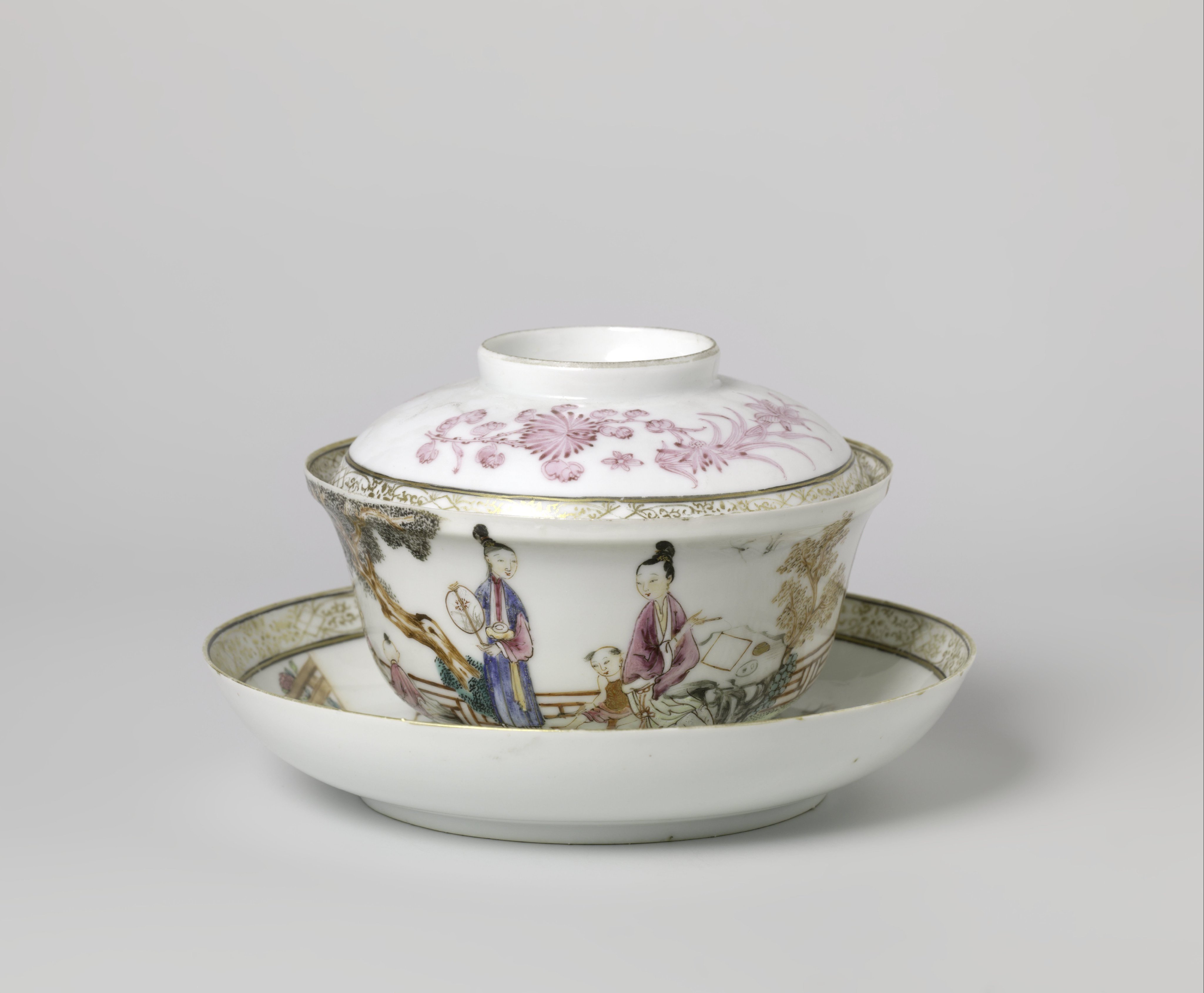 Covered cup and saucer with two women and three boys in a fenced garden