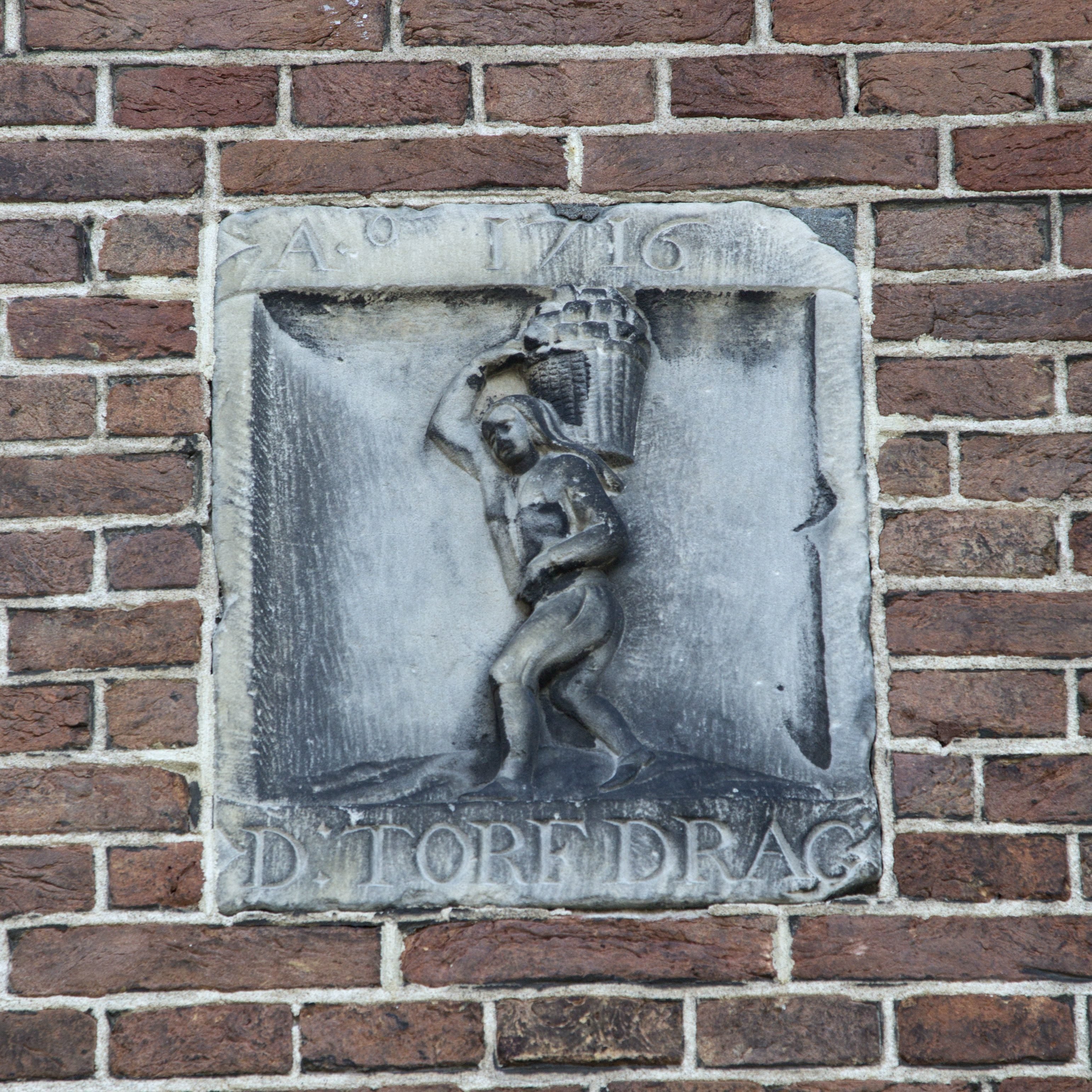 Een gevelsteen met opschrift: DE TORF DRAG
