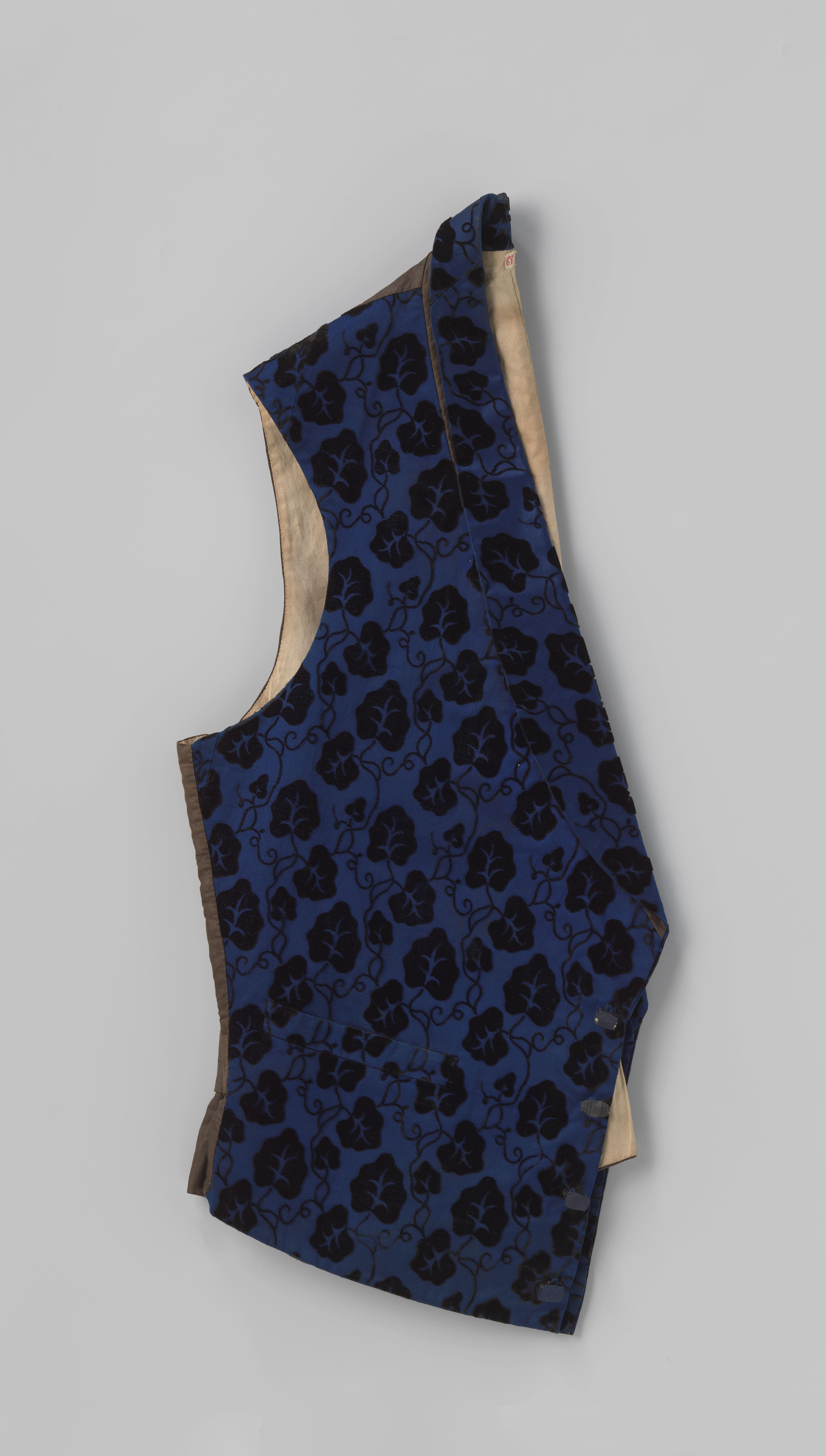 Vest met sjaalkraag, twee steekzakken en vier rolvormige passementknopen van blauwpaarse zijde, versierd met zwarte fluwelen bladranken; rug van bruine geglansde katoen