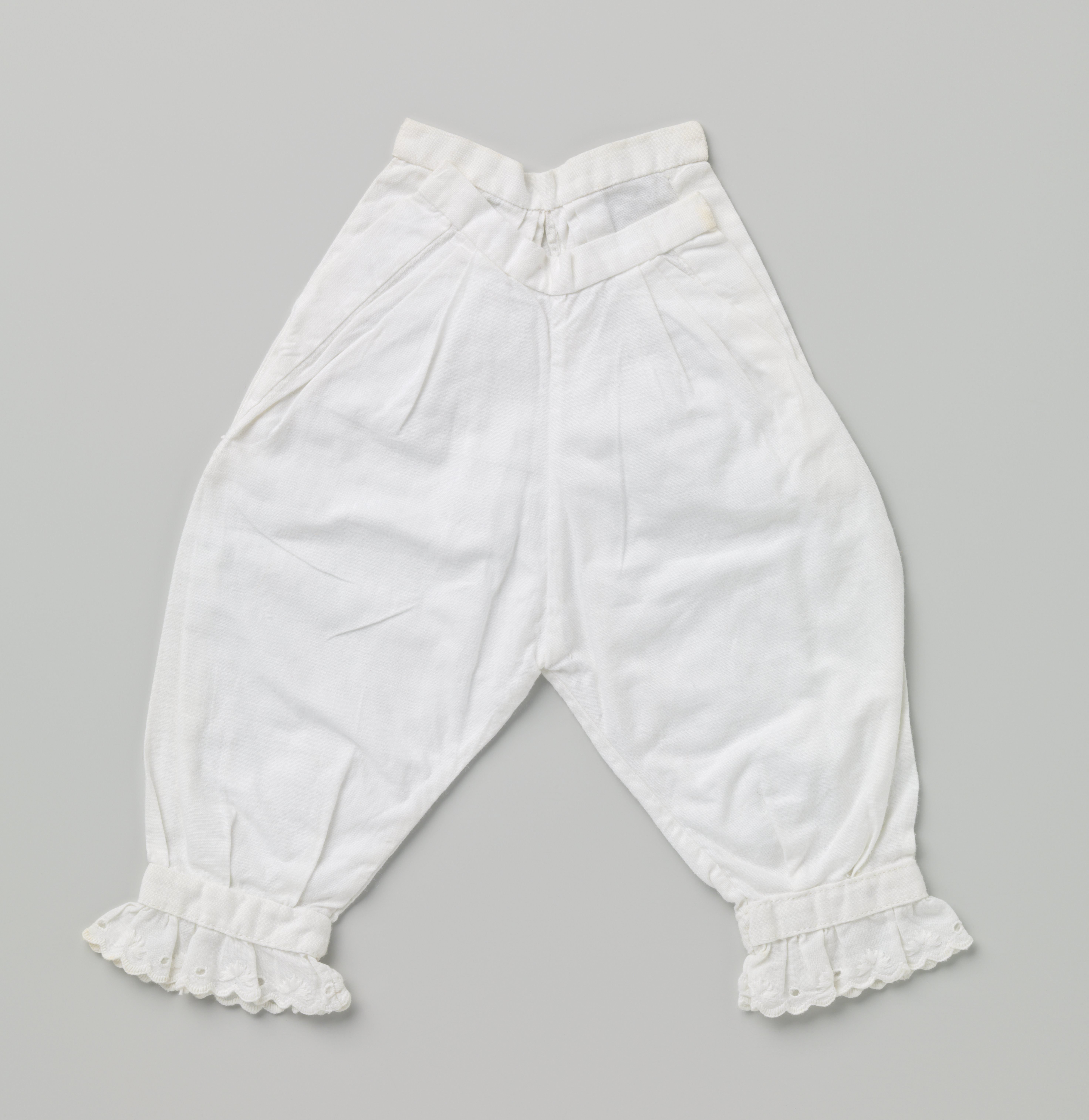 Broek voor baby met gerimpeld aangezette geschulpte kantrand aan de pijpen