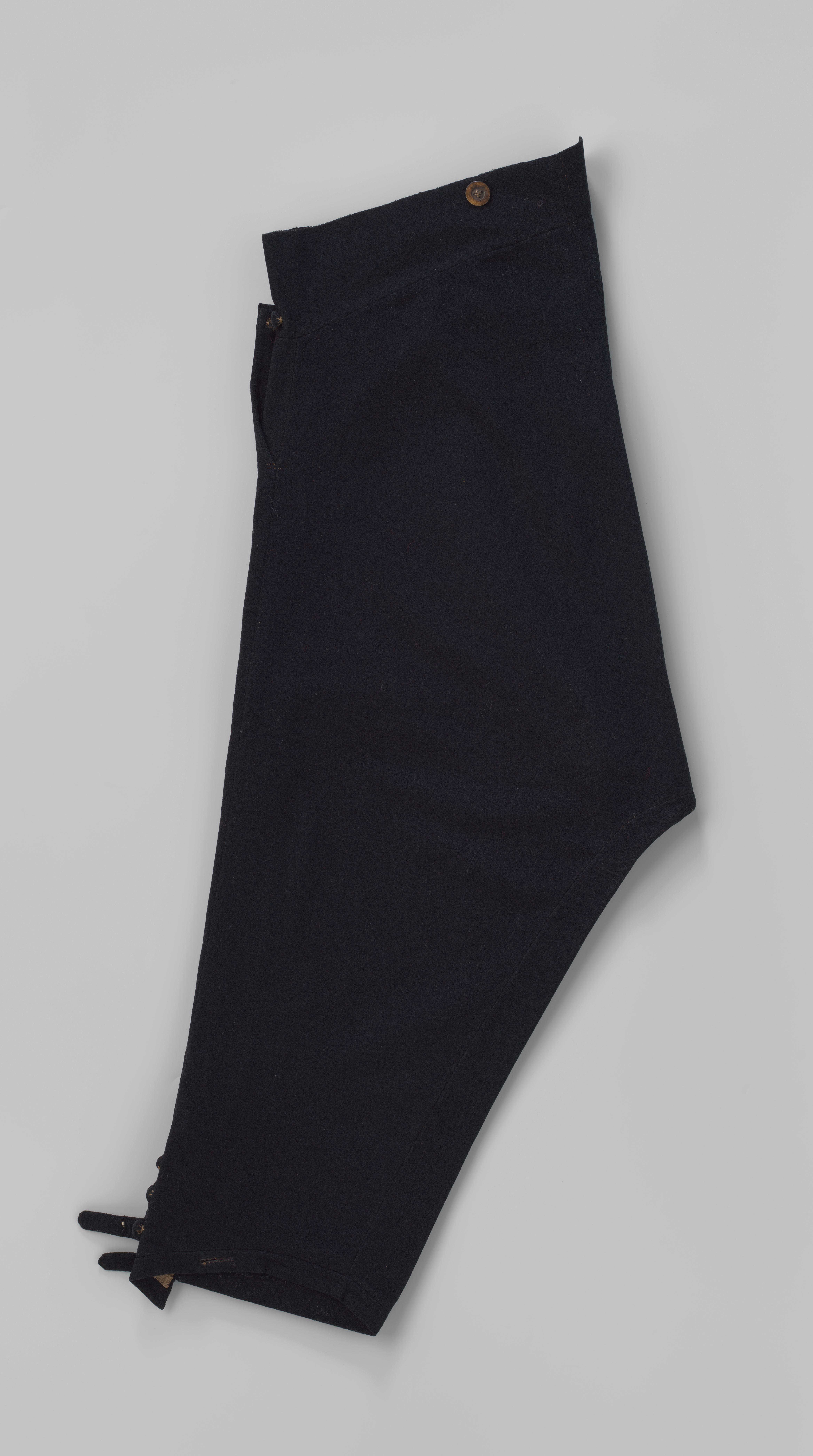 Kniebroek met voorklep, twee zakken met klep en knoop, voorsluiting met 2 knopen naar binnen en 2 knopen naar buiten en pijpen met 4 knopen en lip; van zwart laken.