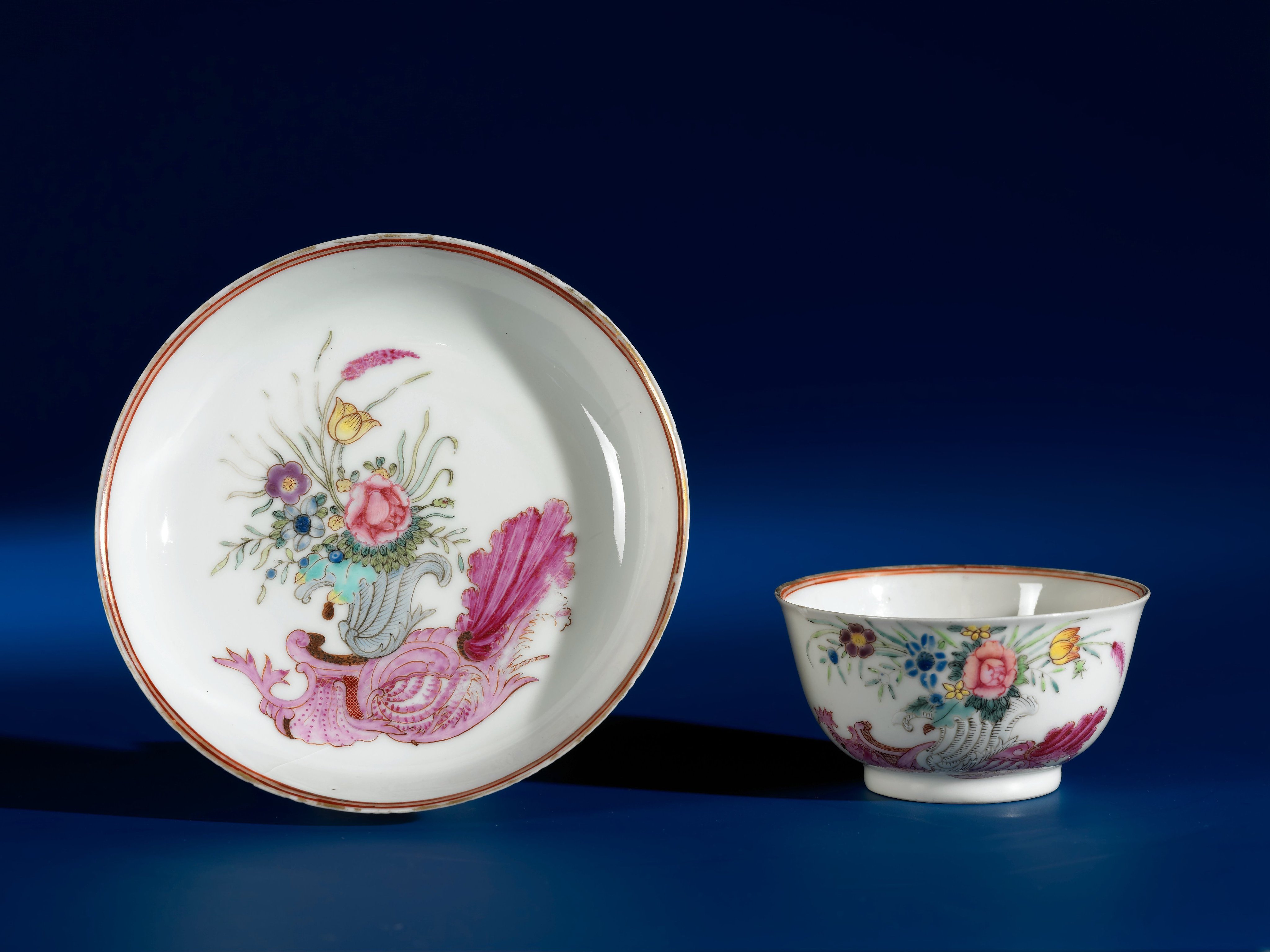 Bell-shaped cup and saucer with a snailornament and flowering plants