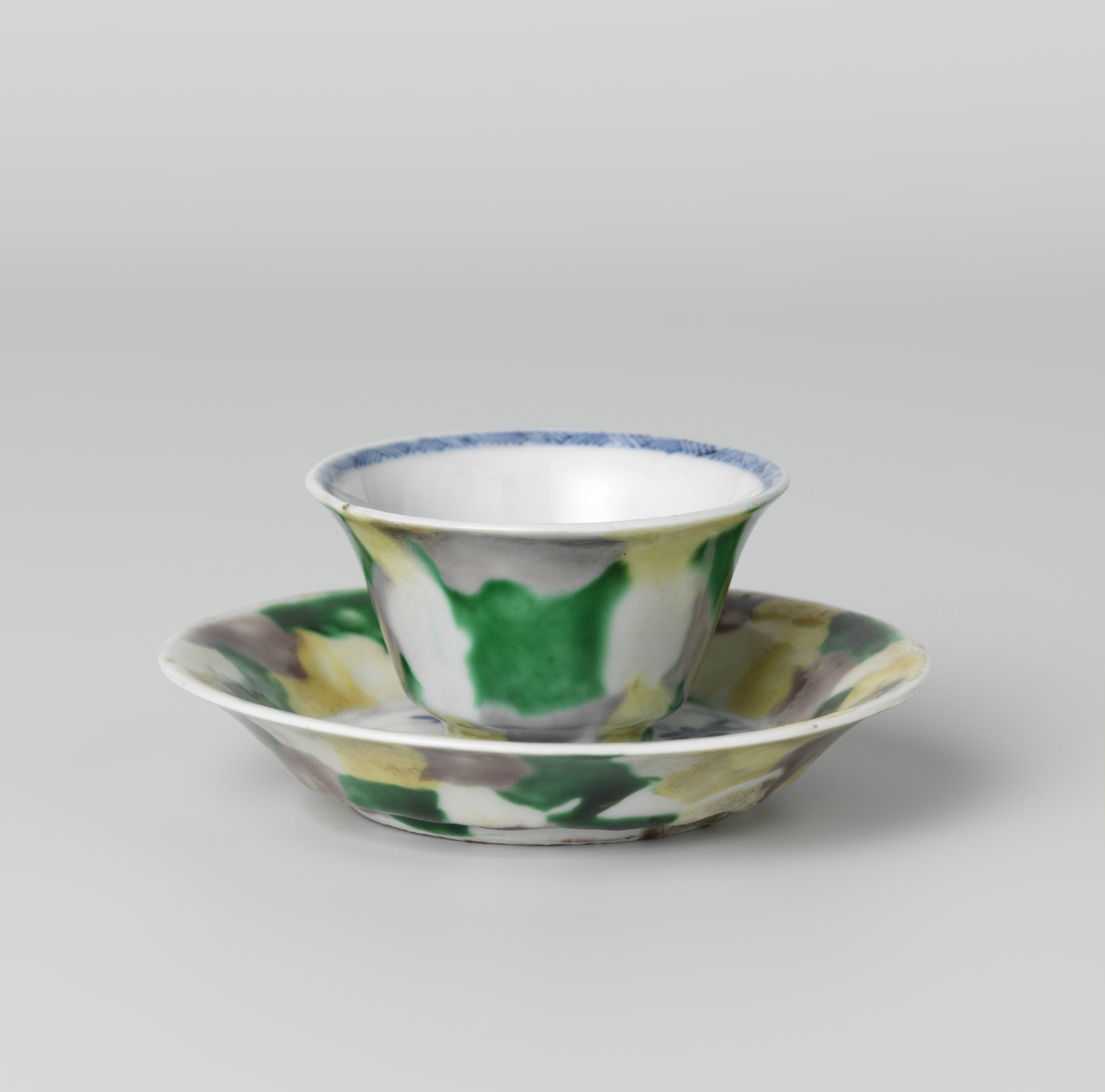 Cup and saucer with 'egg and spinach' pattern and cock among plants