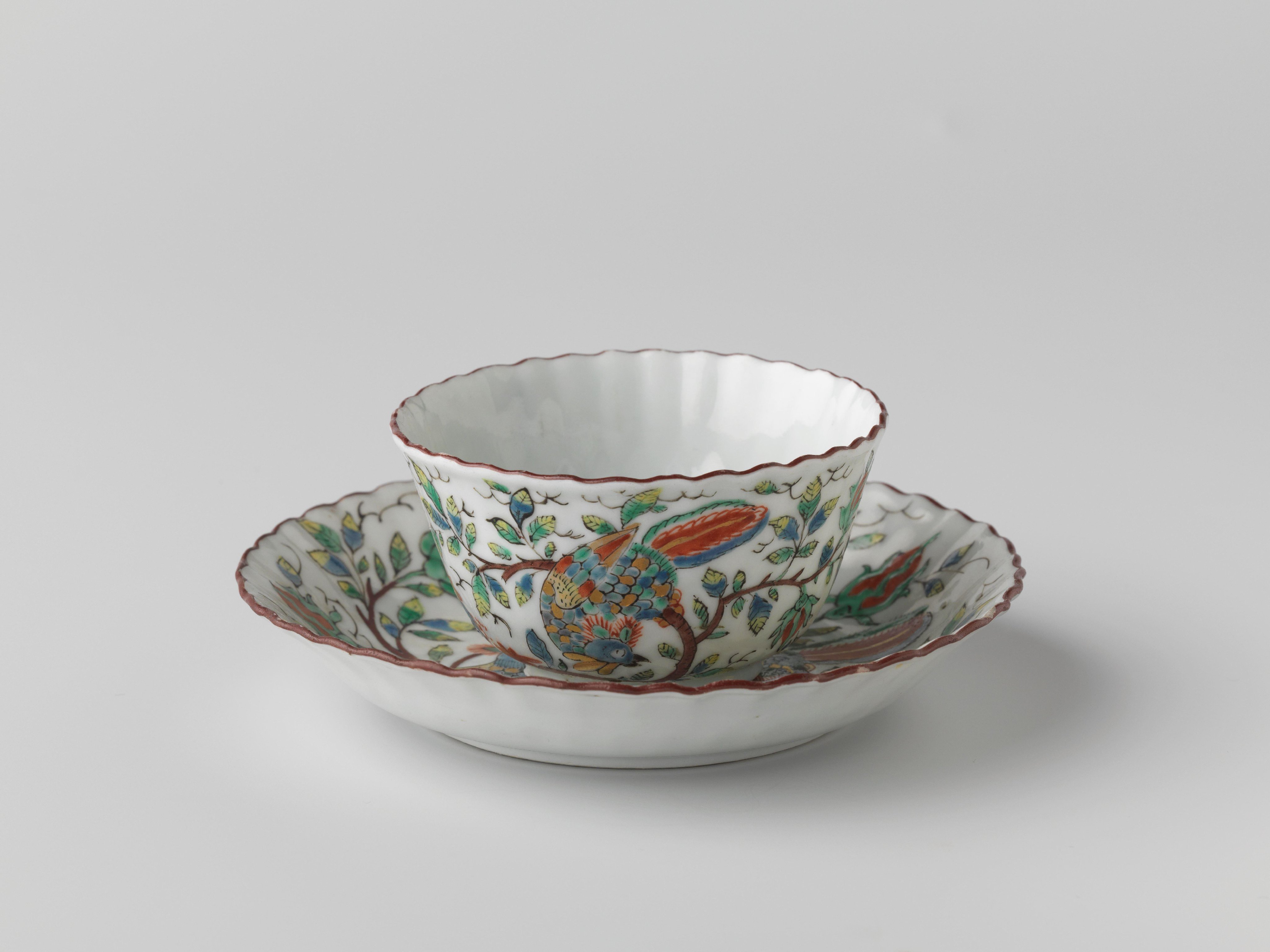 Bell-shaped cup and saucer with fluted sides with two birds on flower sprigs near a rock
