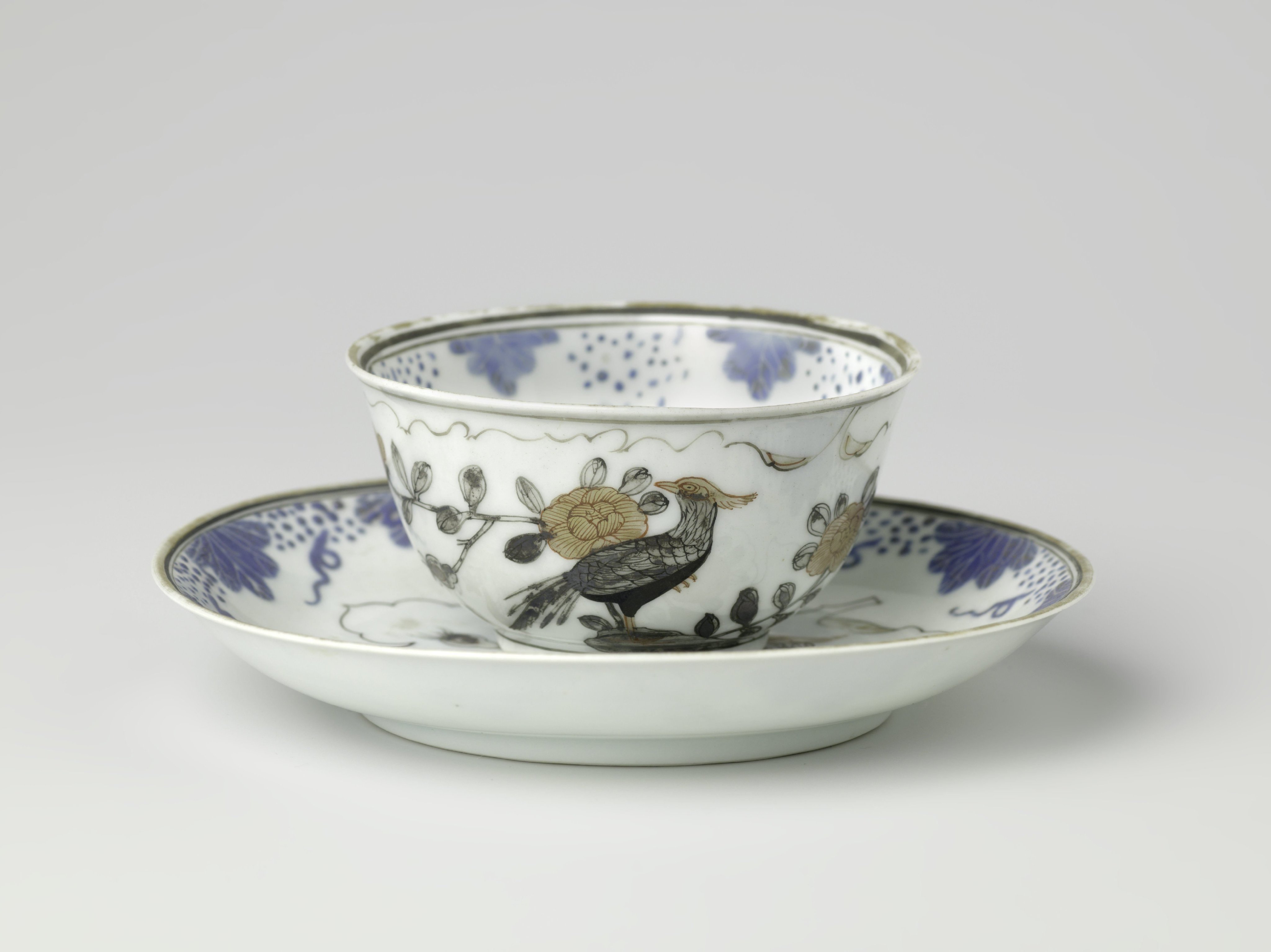 Bell-shaped cup and saucer with two pheasants on a rock in a leaf-shaped panel