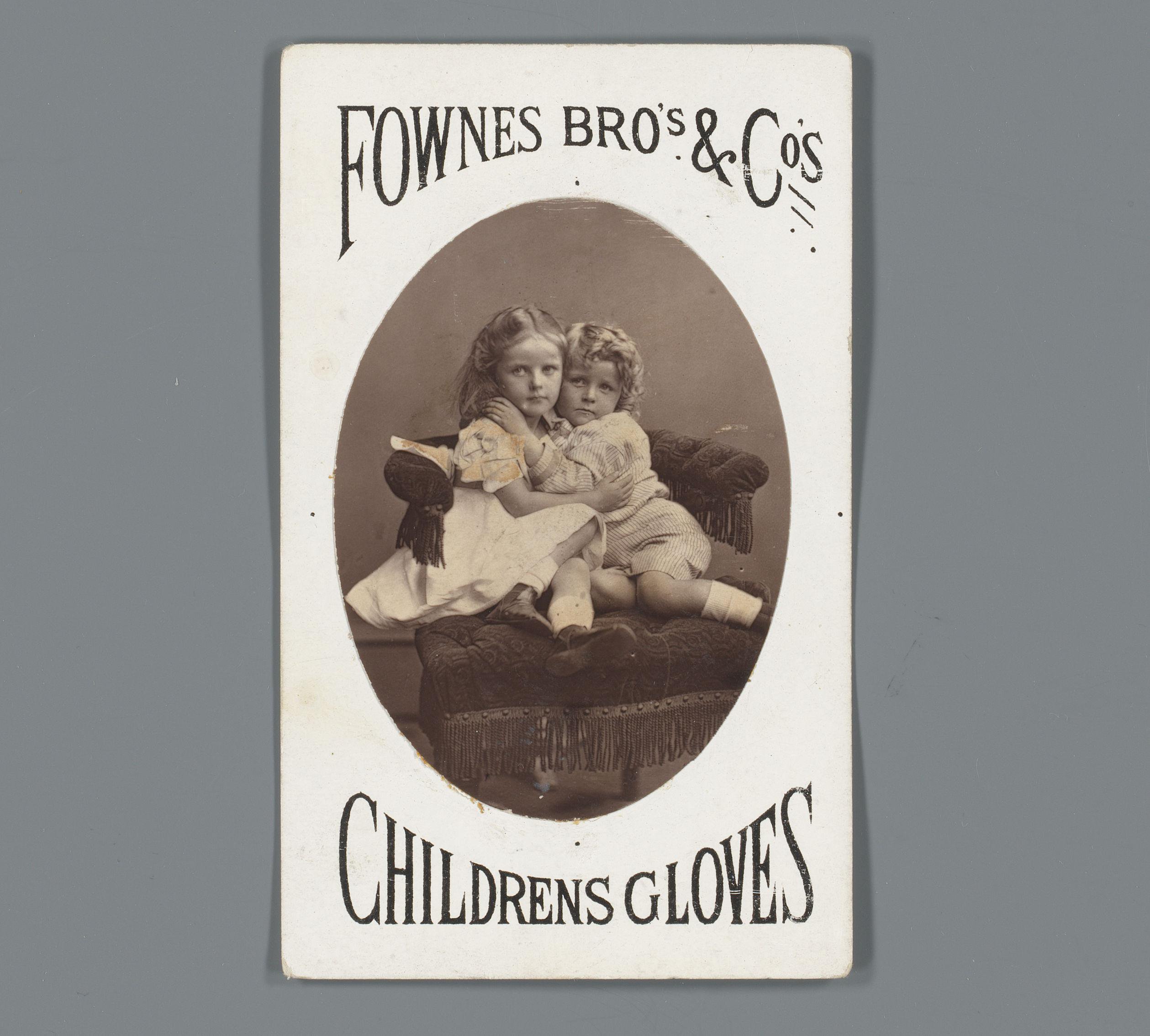 Portret van twee kinderen in een fauteuil als reclame voor kinderhandschoenen van Fownes Brothers & Cos