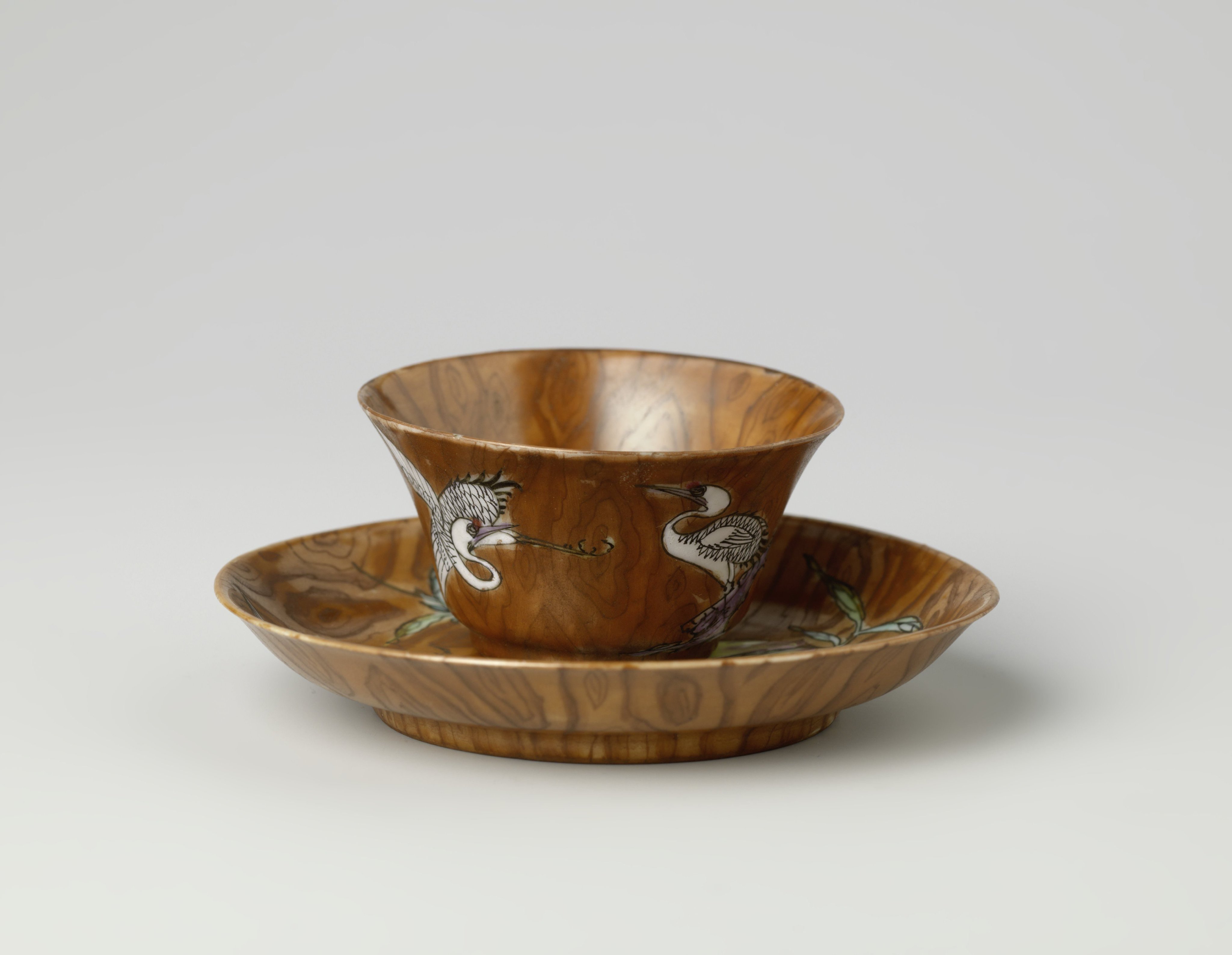 Cup and saucer with peachtree and crane on a woodcolored ground