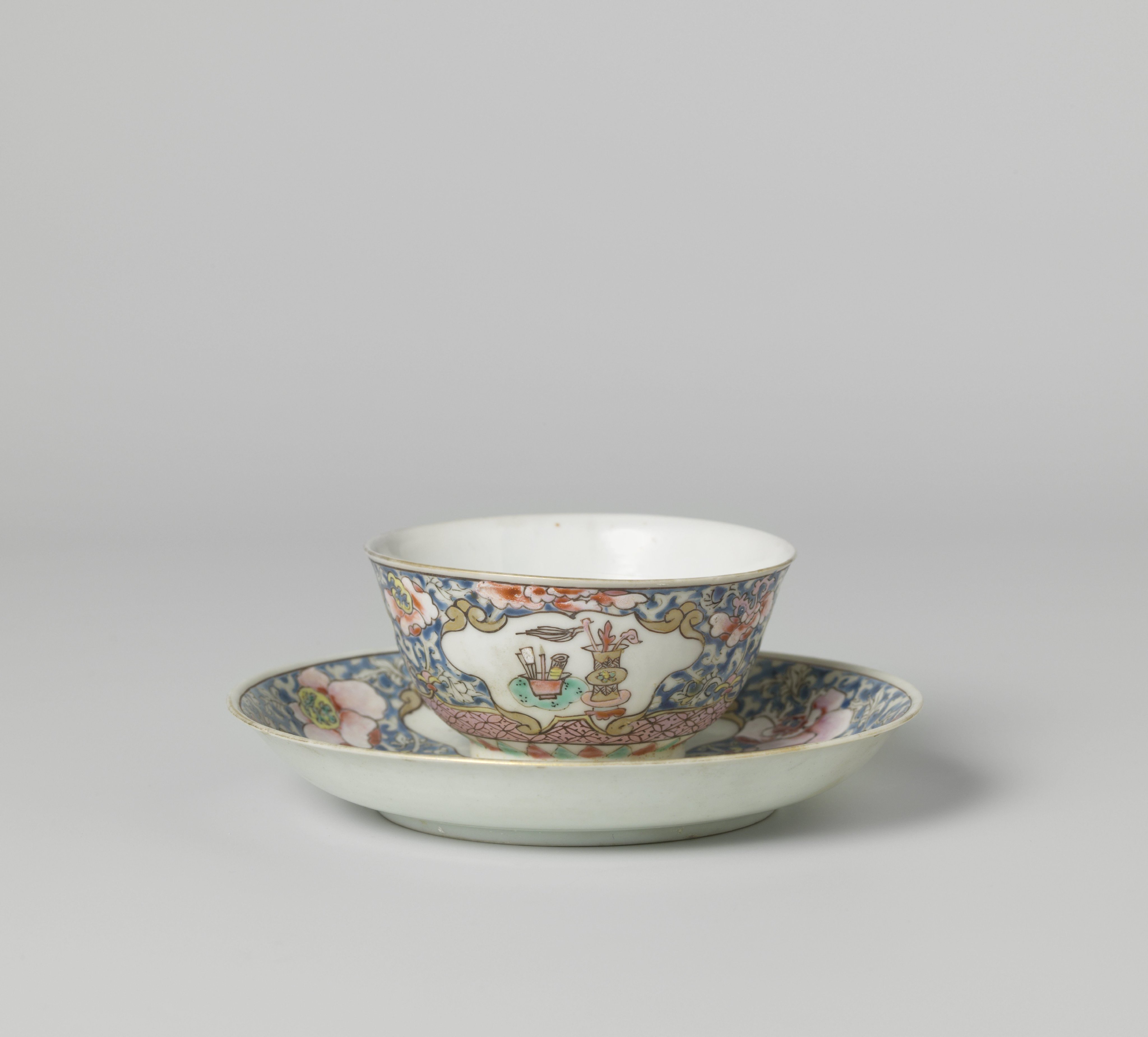 Bell-shaped cup and saucer with antiquities in panels on a ground of floral scrolls