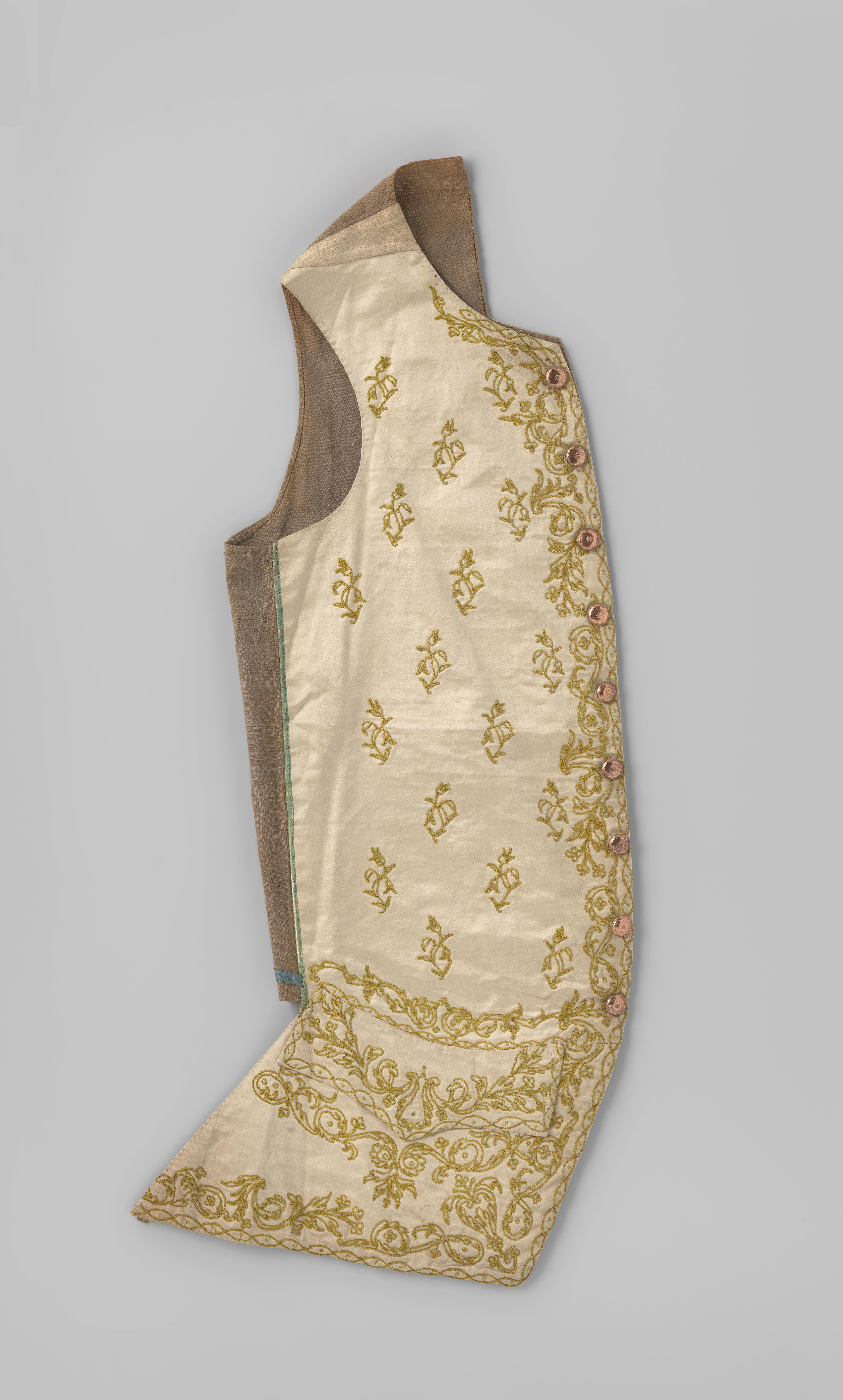 Lang mouwloos vest met 9 koperen knopen met bloem, van crème satijn, in felgroen en chenille geborduurd met floraal strooi- en randmotief en quilloche; linnen voering en rug.