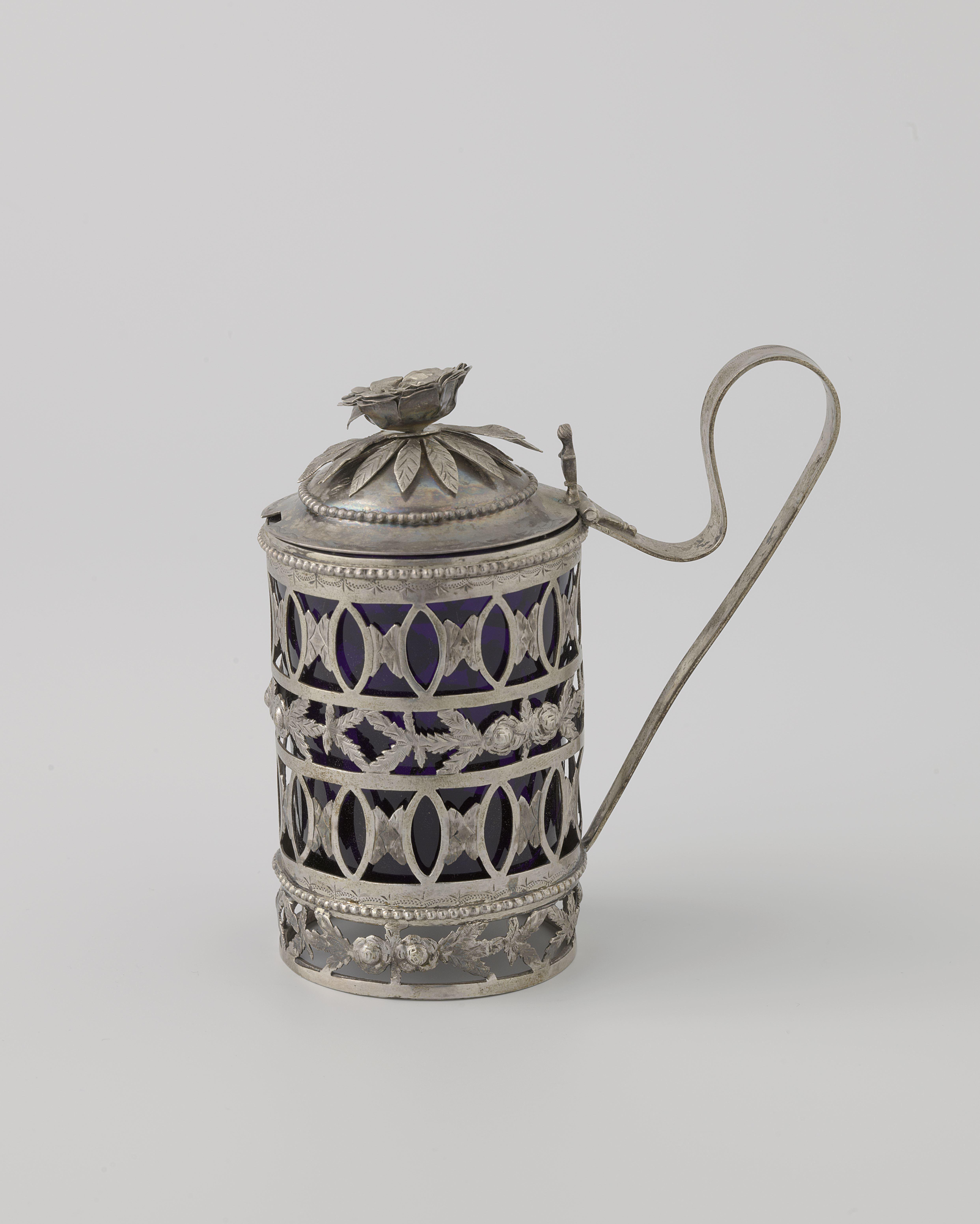 Mosterdpot van zilver, rond, met vier opengewerkte randen. Binnenbak van blauw glas.