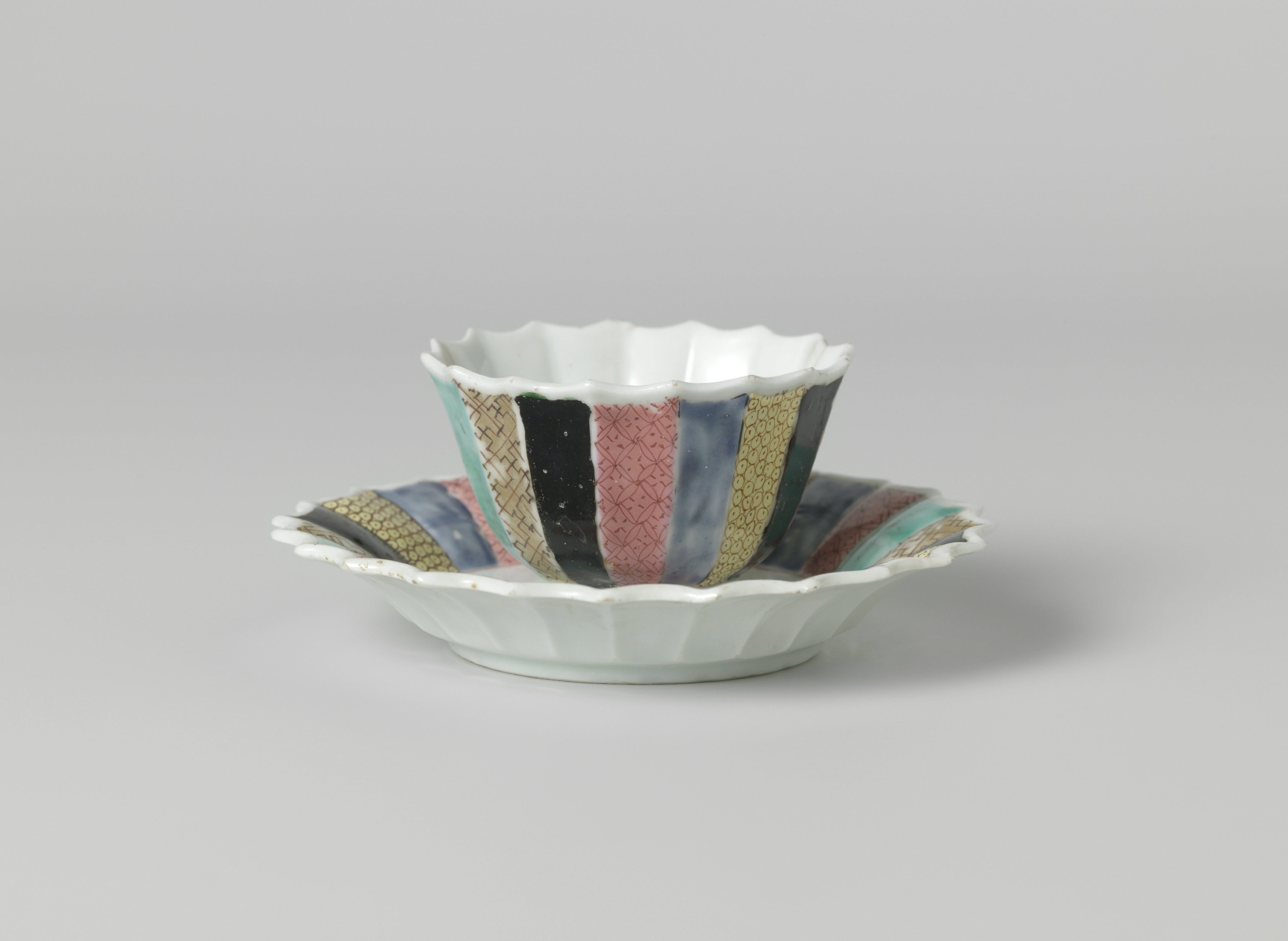 Bell-shaped cup and saucer with a woman in a garden and diaper patterns on various colored grounds