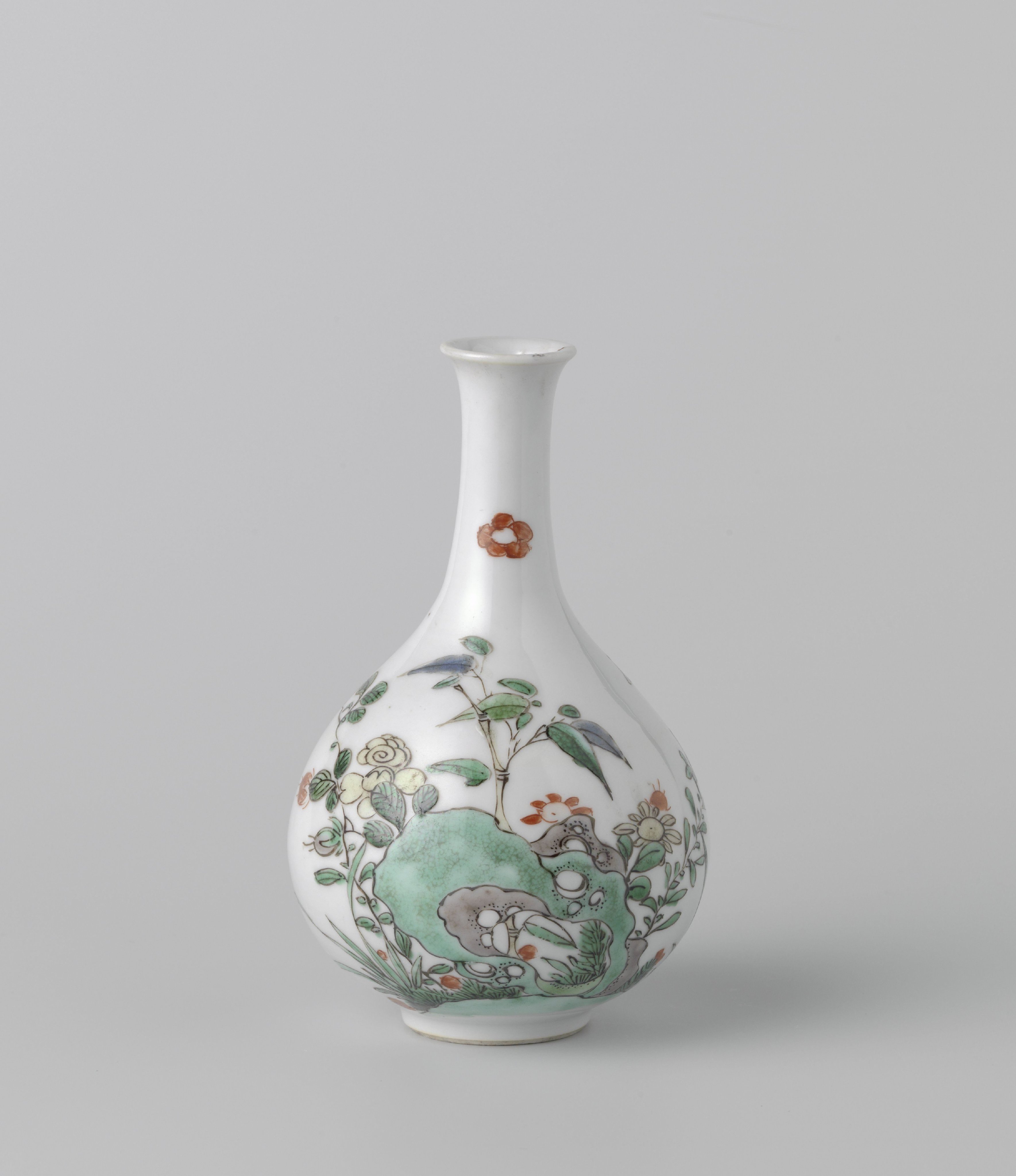 Bottle vase with flowering plants near a rock
