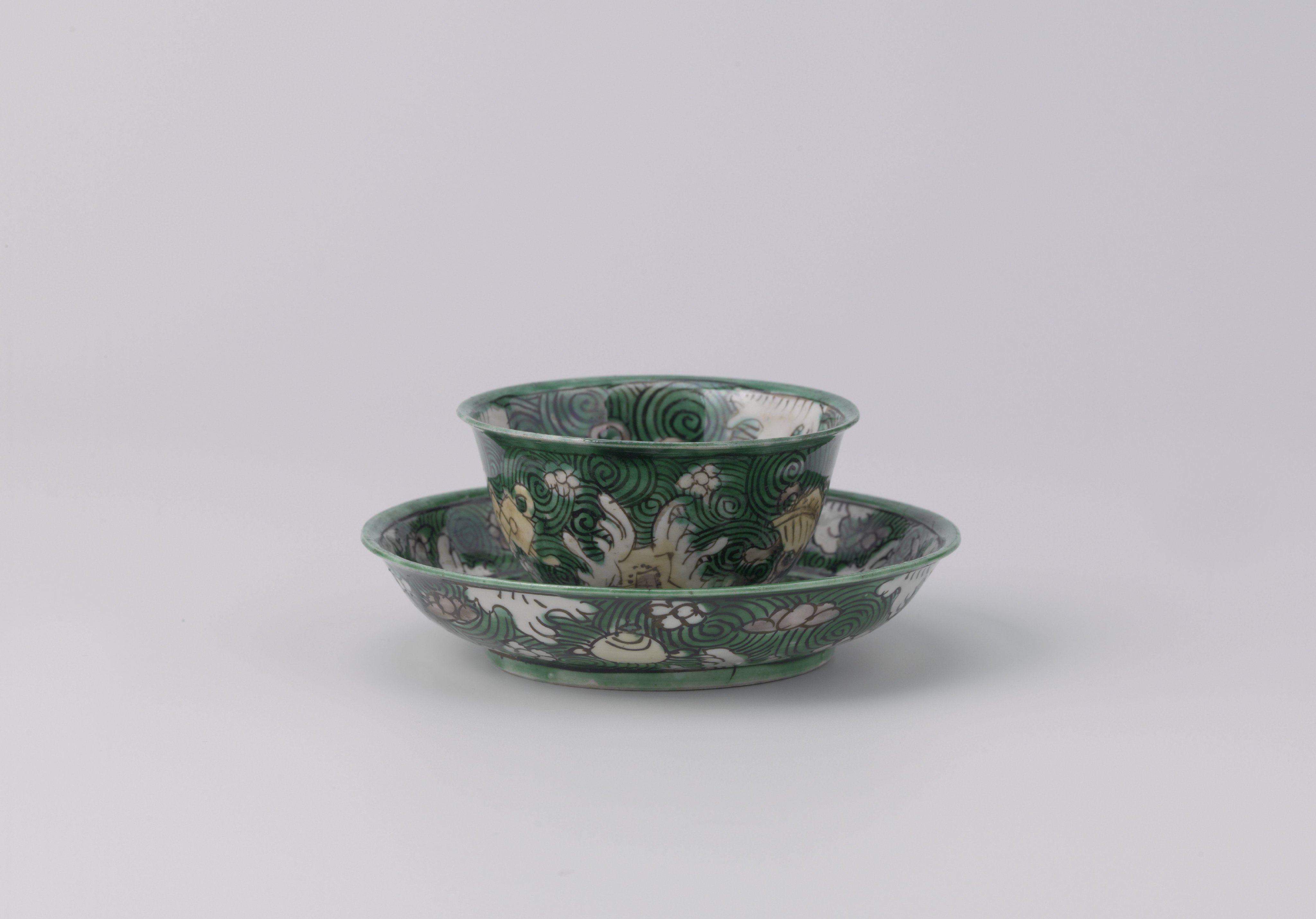 Cup and saucer with precious objects on a green ground with cloud motifs