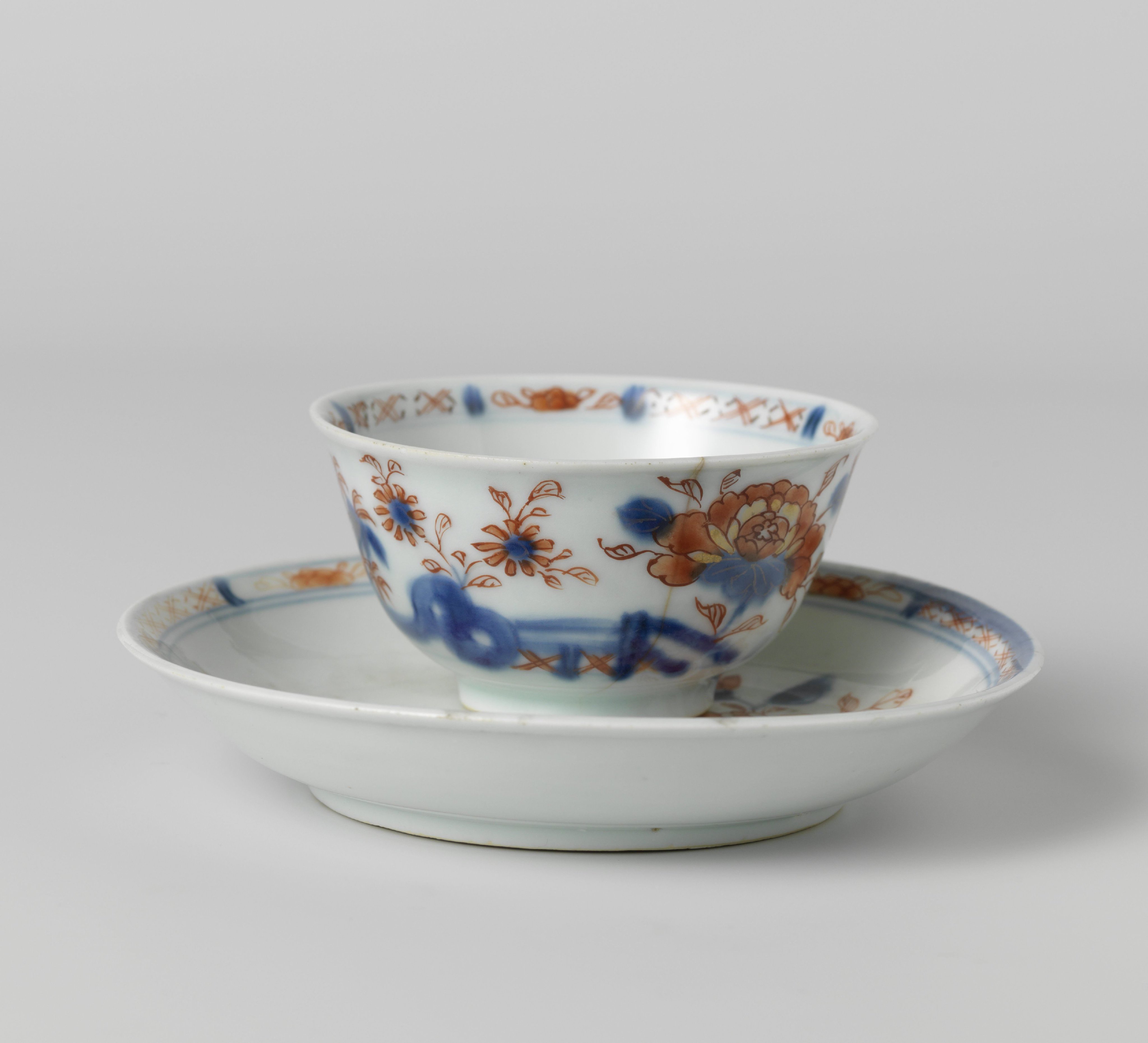 Cup and saucer with flower sprays behind a rock and fence