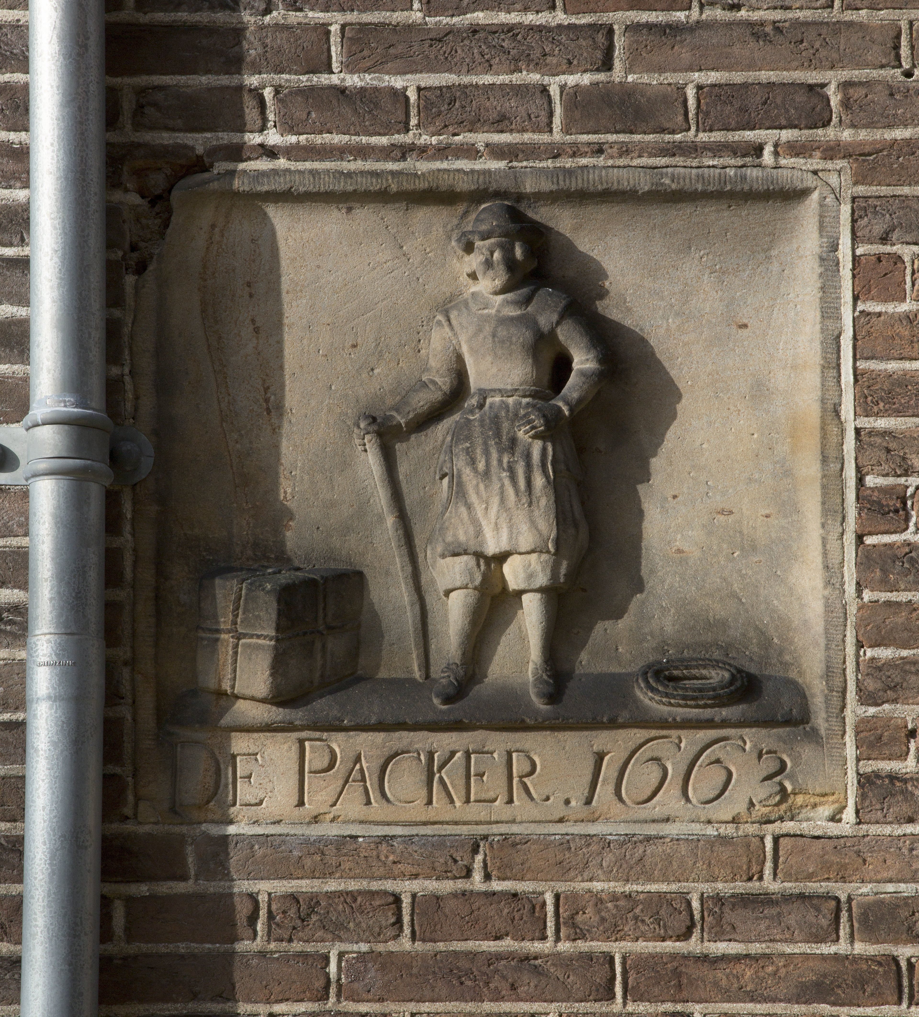 Gevelsteen met staande man met pakket en touw en opschrift: DE PACKER 1663