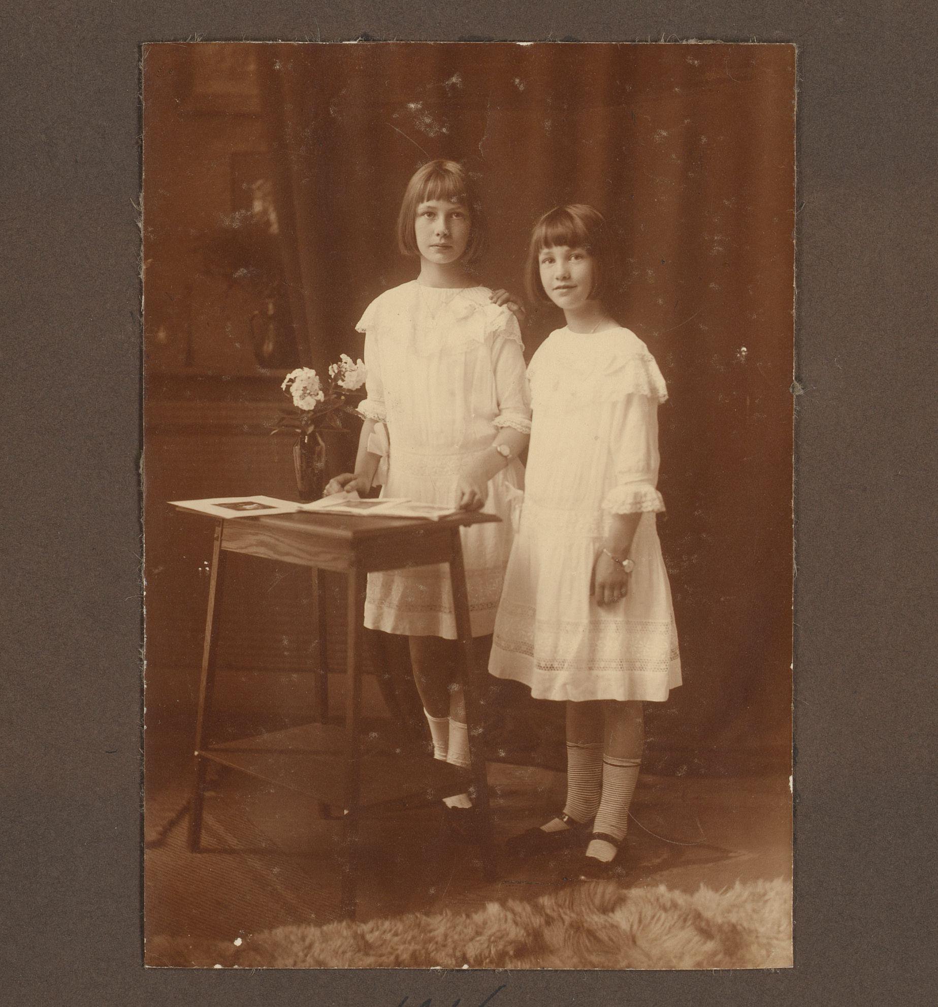 Portret van Joanna en Thea Diepenbrock staand aan een bijzettafel met daarop een vaas bloemen