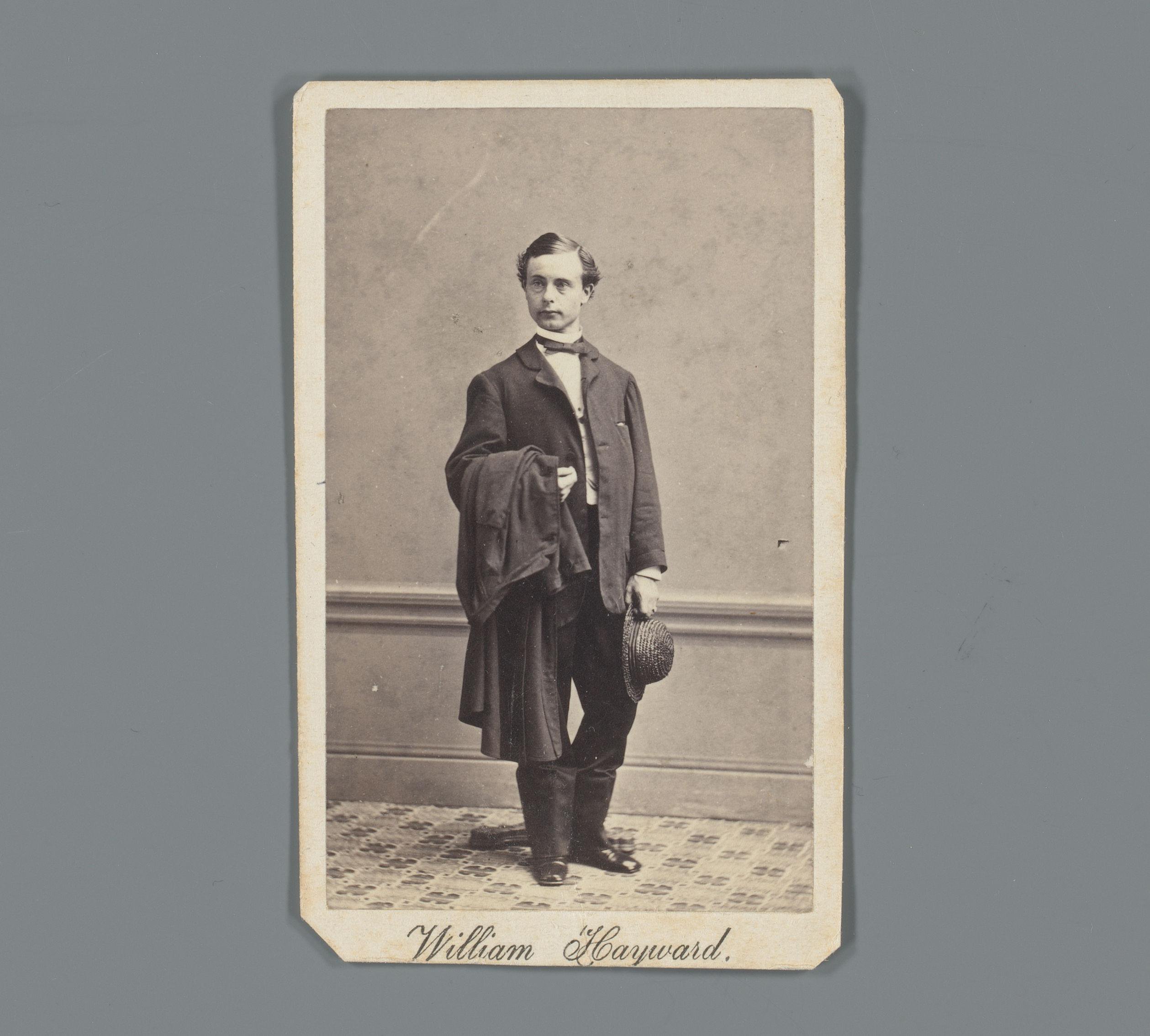 Portret van William Hayward staand met jas en hoed in de hand
