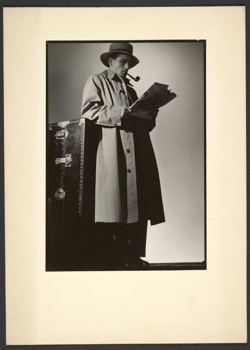 [Man in trench coat reading newspaper]