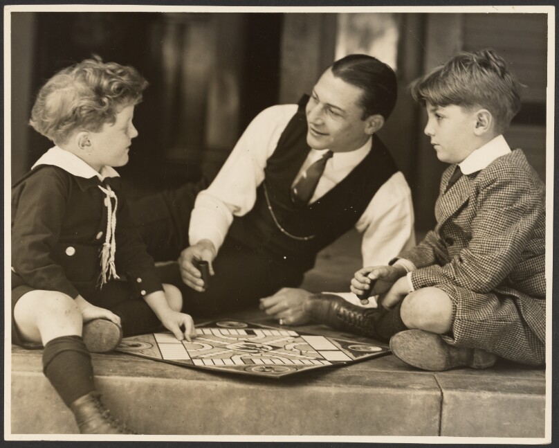 [Man playing a board game with two boys]