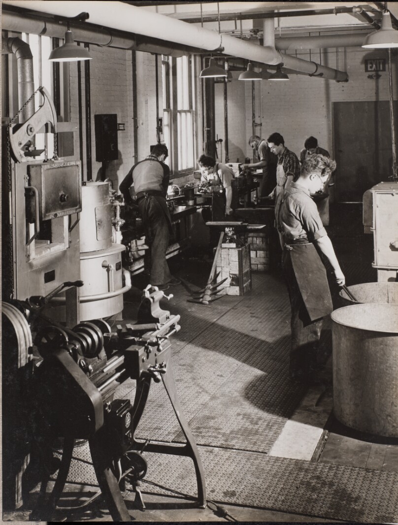 [Six men work in a welding workshop]