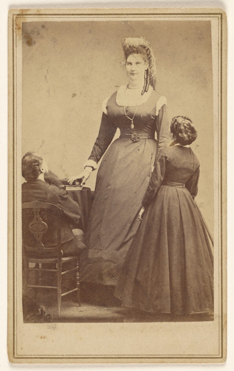 [Anna Swan standing in front of two average sized people.]