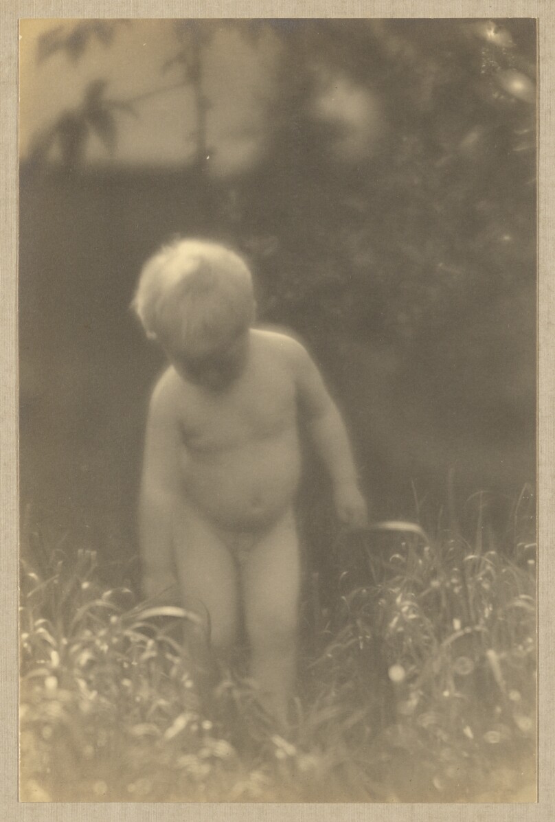 [Brett Weston, nude, standing in field, looking downward]