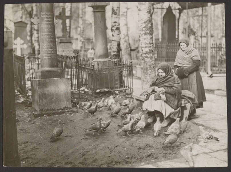 Old Beggar in the churchyard feeding the pigeons.