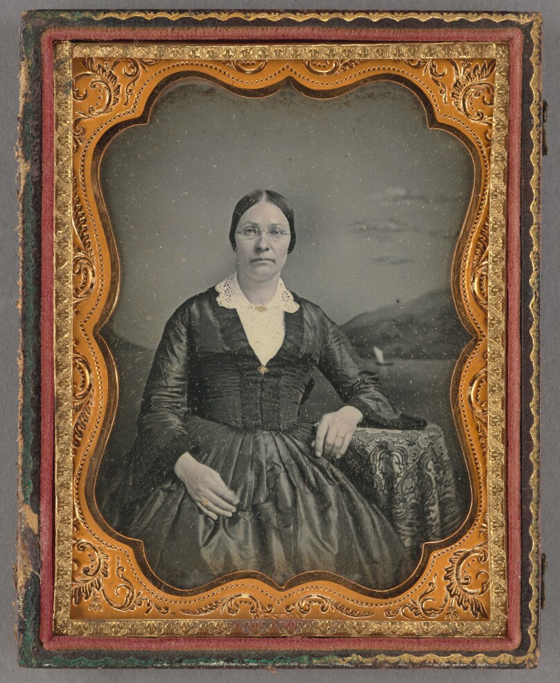 [Portrait of a seated middle-aged woman wearing wire-rimmed glasses]