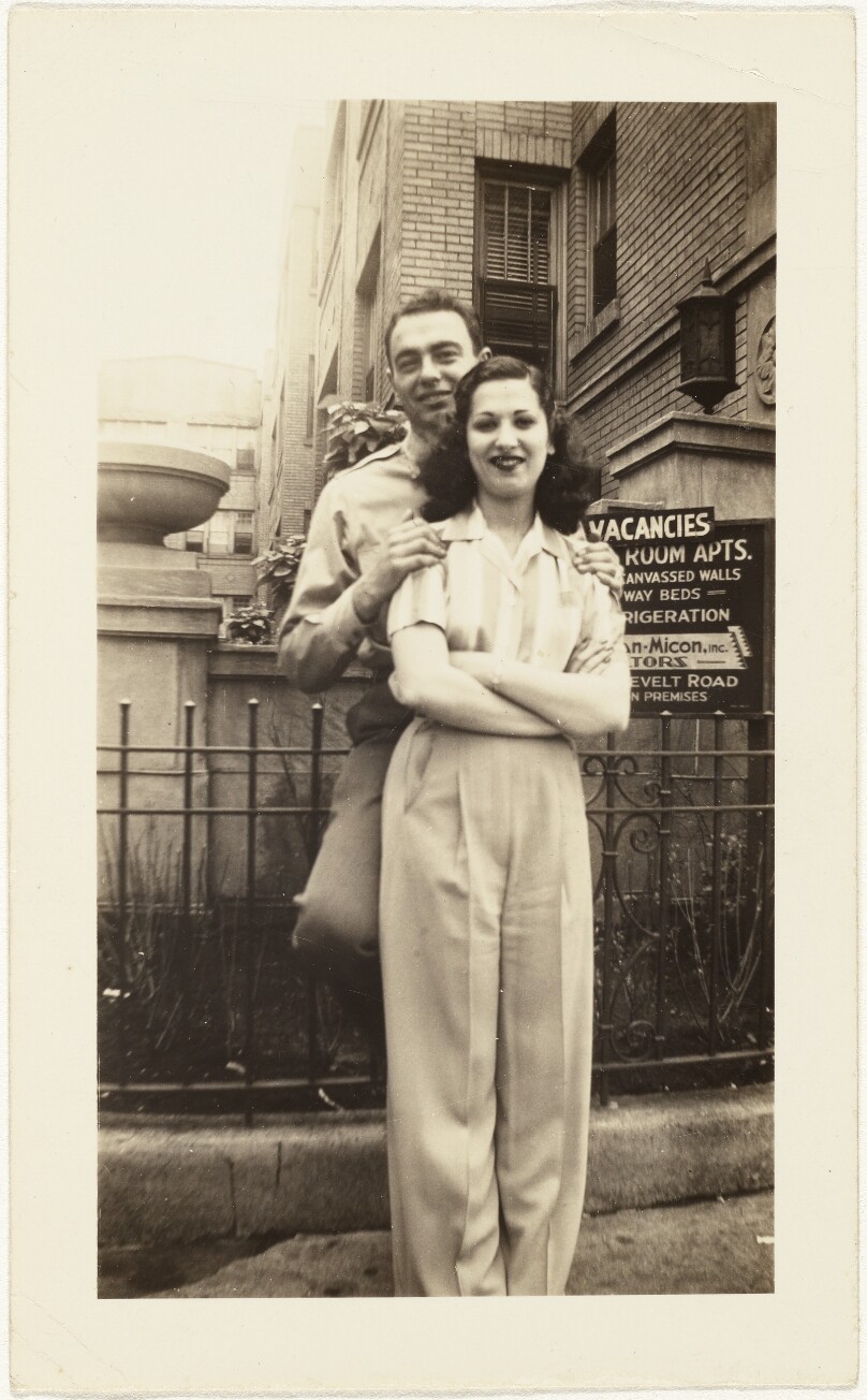 [Man and woman in front of apartments]