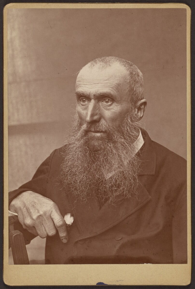 [Portrait of a man with sideburns and a beard]