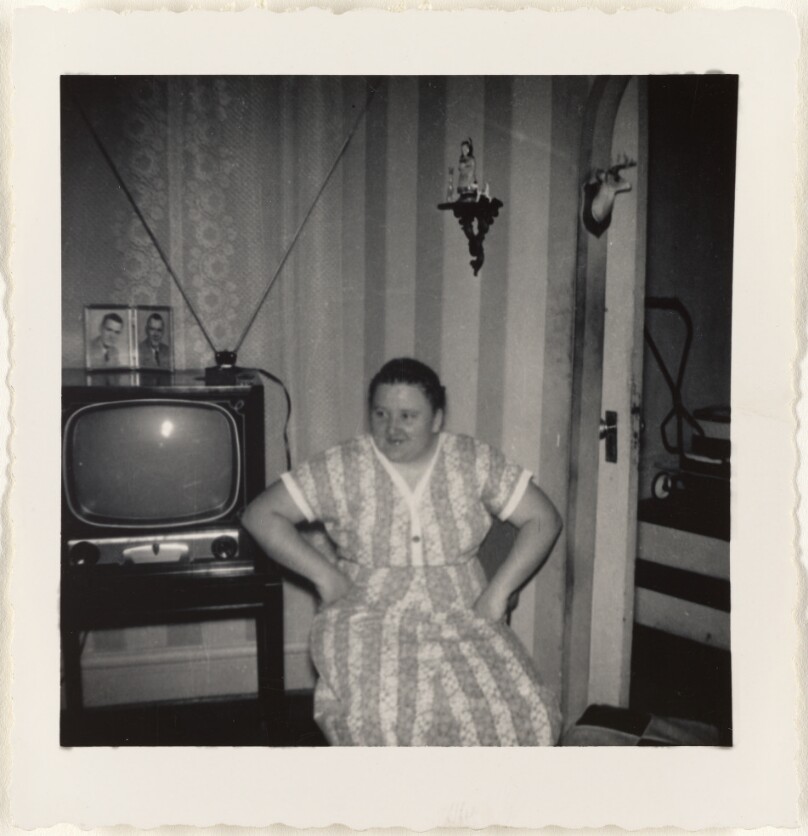 [Seated woman beside television set]