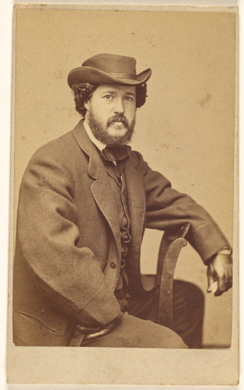 [Unidentified bearded man wearing a hat, seated]