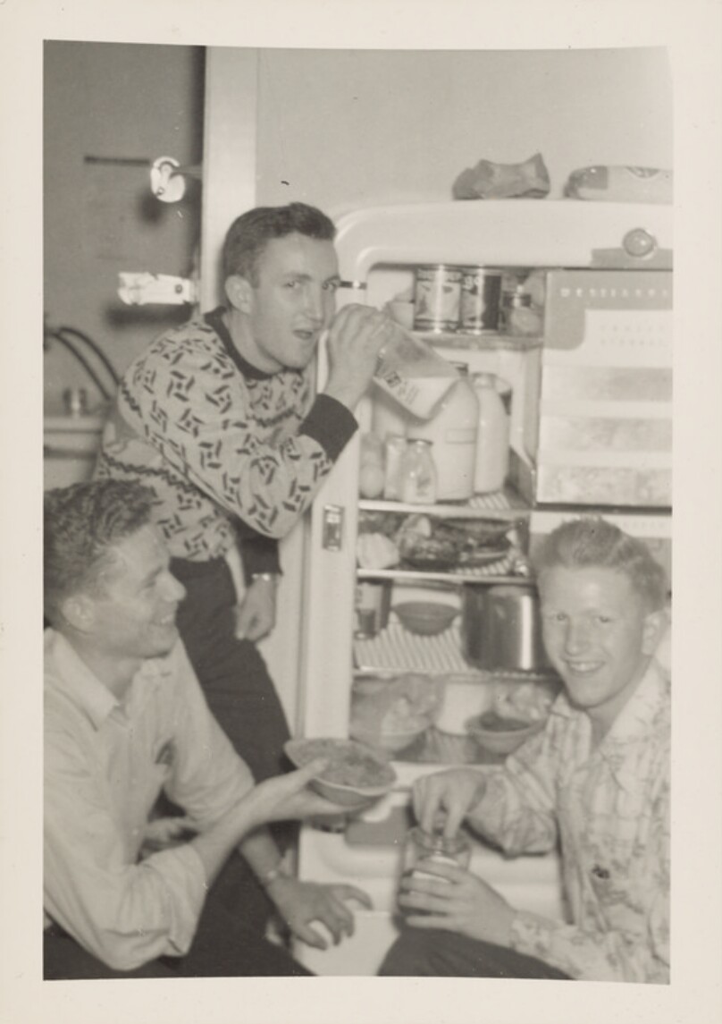 [Three young men gathered around a refrigerator]