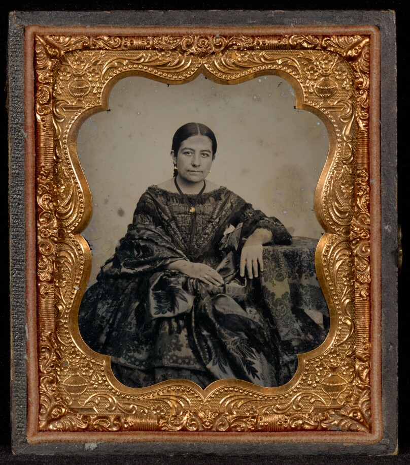 [Portrait of a Woman in a Full Dark Dress Seated at a Table]