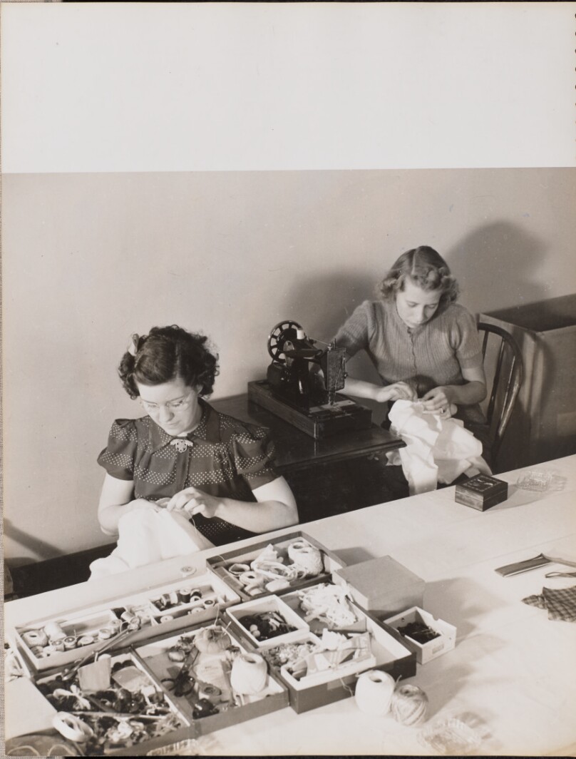 [Two women sew fabric by hand]
