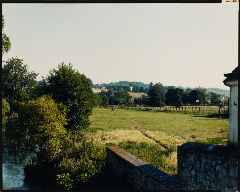 [Figures walking across field near river]