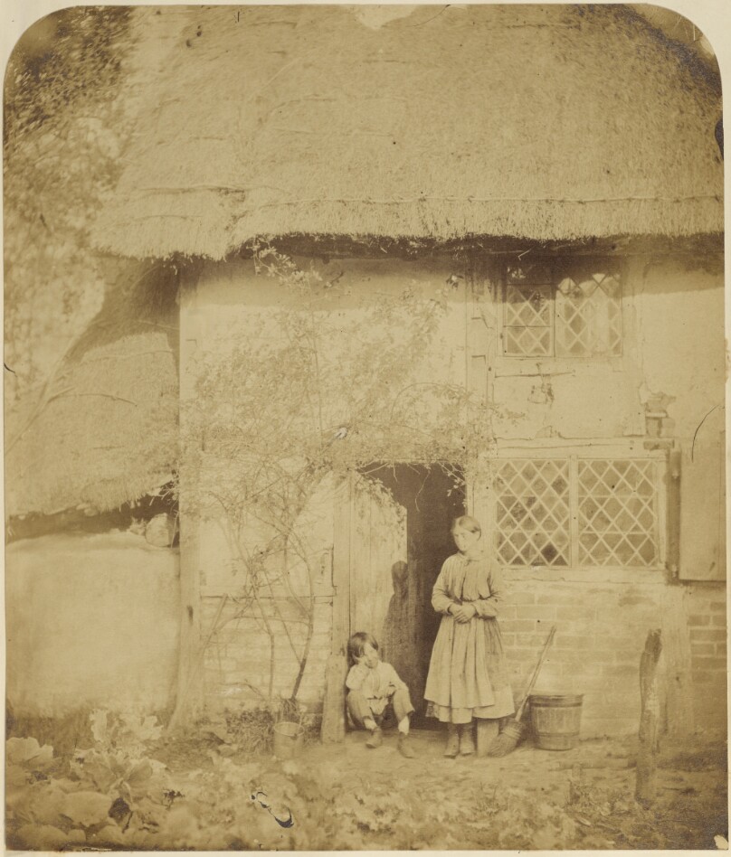 [Woman and boy in front of cottage]