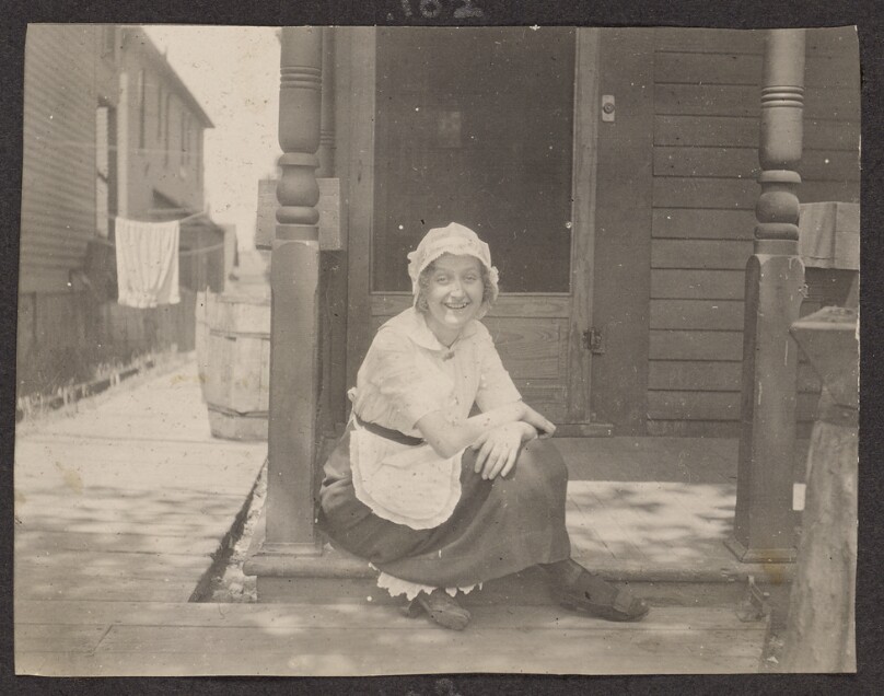 [Woman sitting on the front porch of a house]