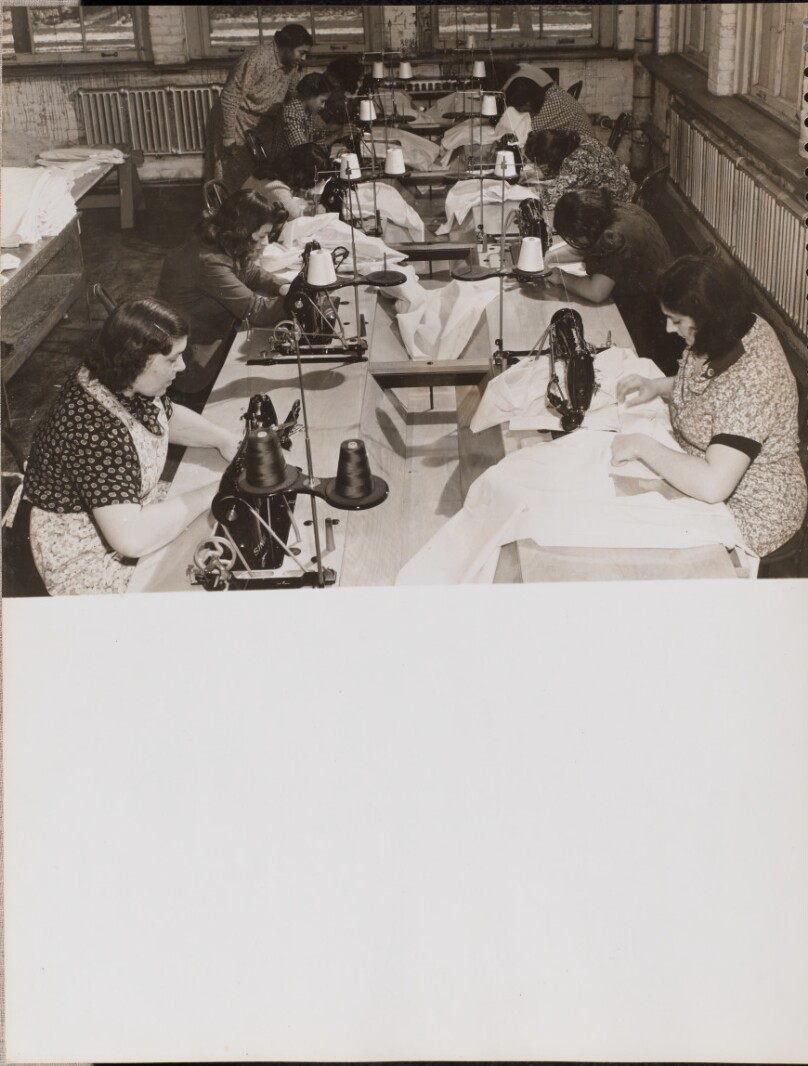 [Two rows of women work on sewing machines]