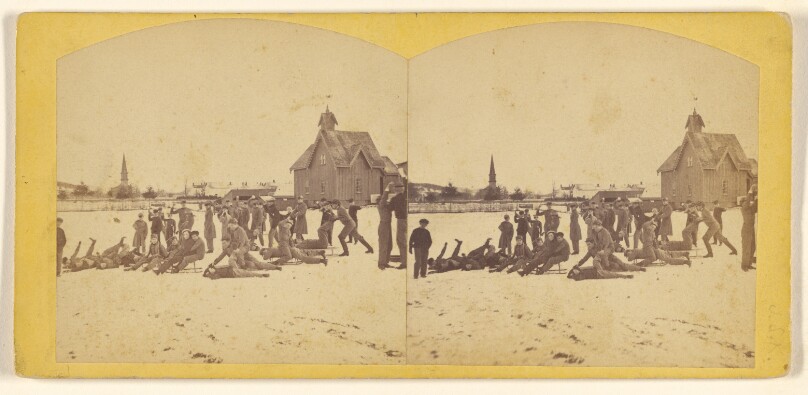 [Group of boys playing in the snow, large house at right in background]