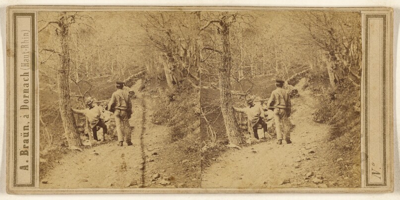[Two men on a forest path with barren trees]