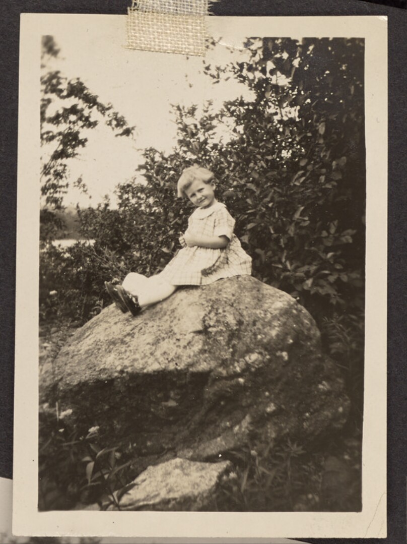 [Child sitting on a rock]