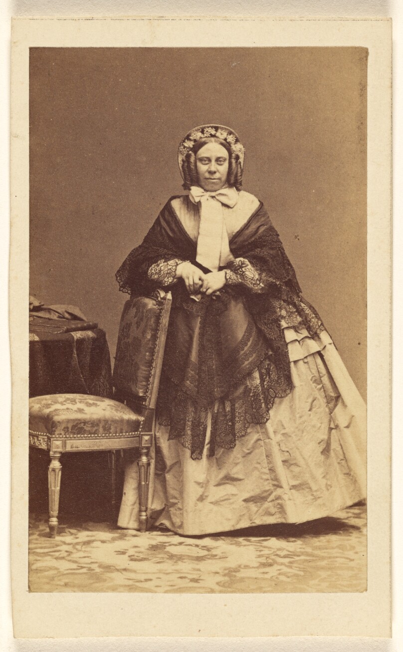 [Unidentified woman with curls wearing a hat, standing]