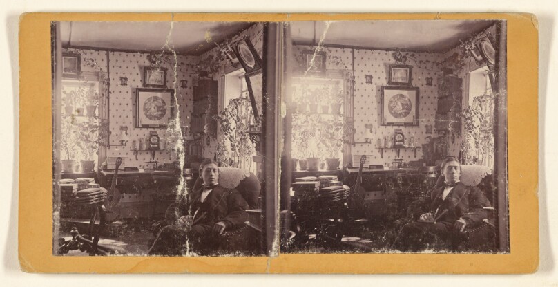 [Young man seated in a room]