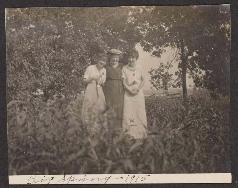 [Three women pose in a field]
