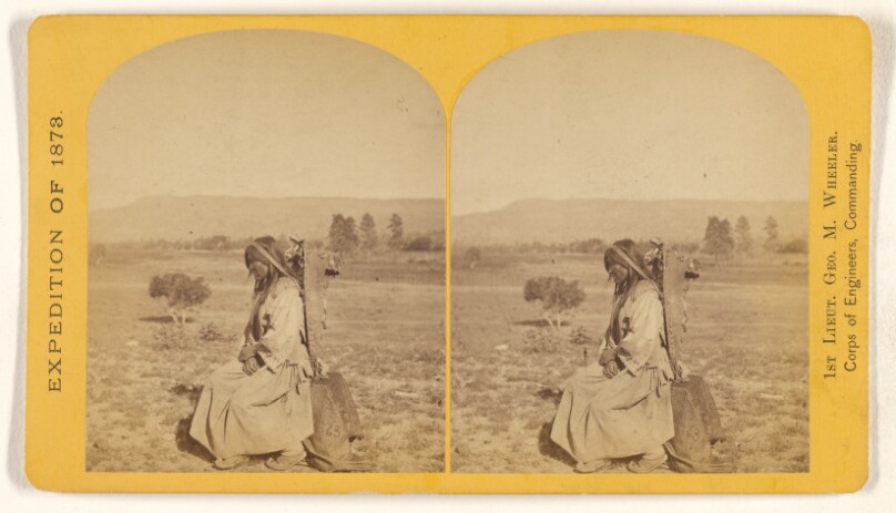 Apache squaw and papposse [sic]. The child is securely lashed in the wicker-work basket or box, and slung to the back of...