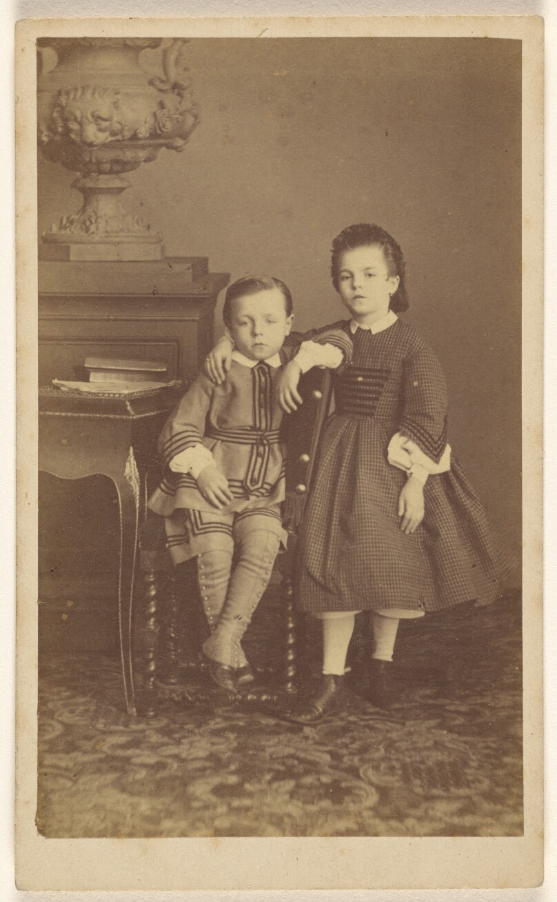 [Two unidentified children: boy, seated, girl, standing]